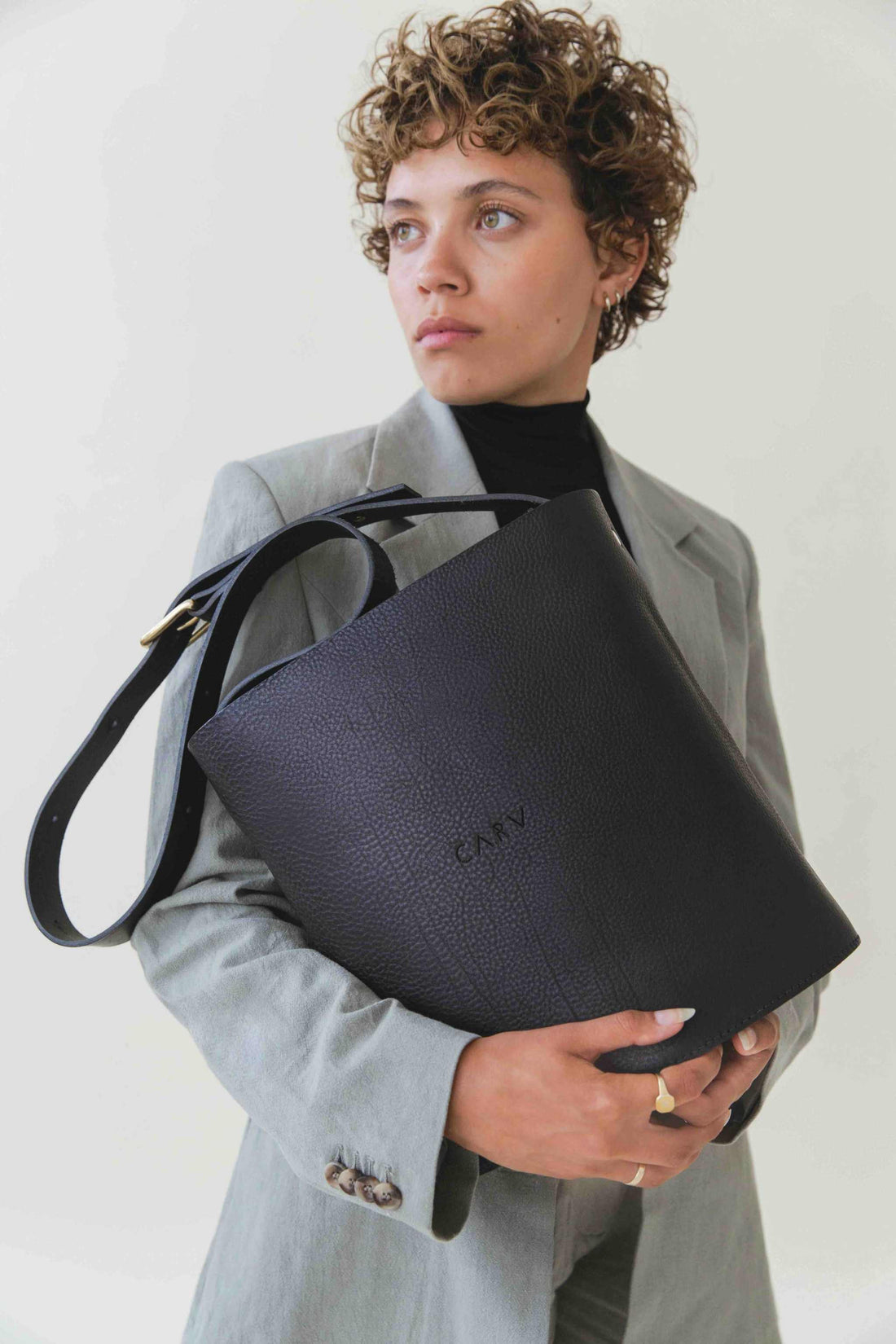 British leather handbag in black held by a model with grey jacket