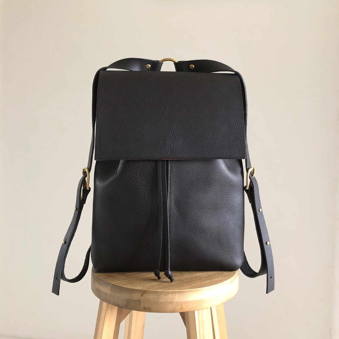 CARV black leather backpack on wooden stool