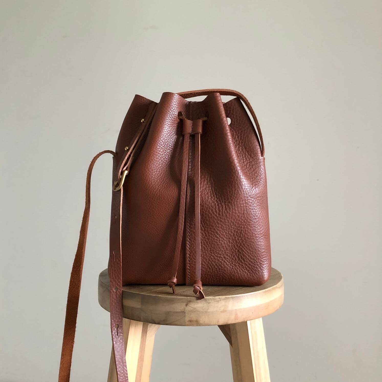 CARV tan leather bucket bag sitting on a stool