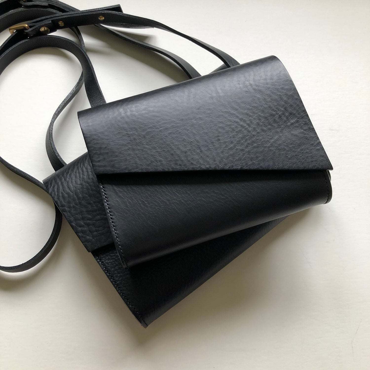 CARV black leather cross body bags stacked on eachother