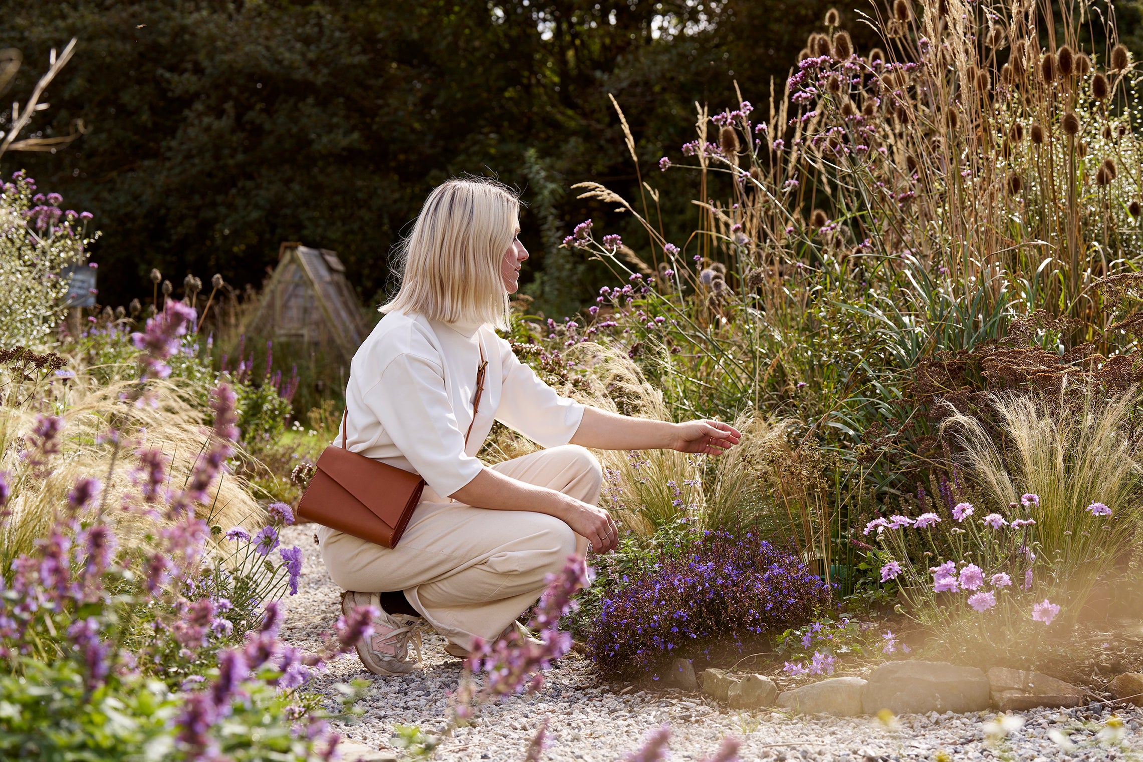 Becky from CARV in the garden of the leather studio in Cornwall wearing a tan leather cross body bag