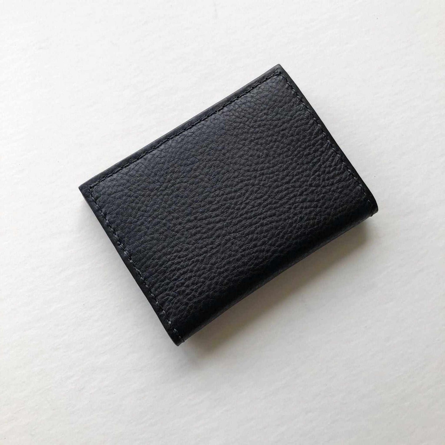 Hand stitched black leather bifold card wallet by CARV on white background.