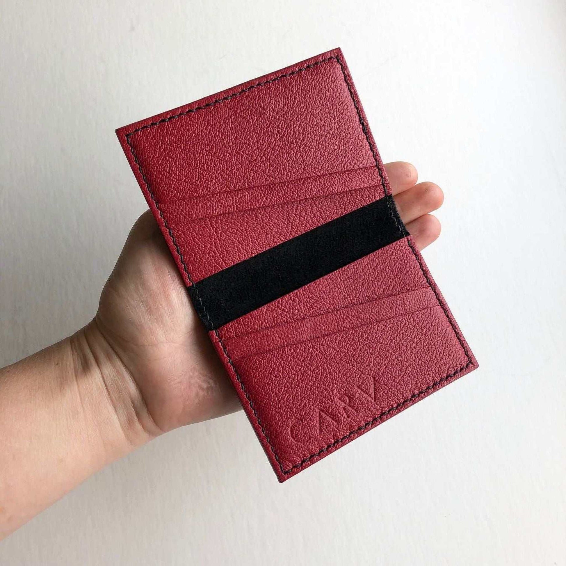 Hand stitched black leather bifold card wallet with red interior and card slots.