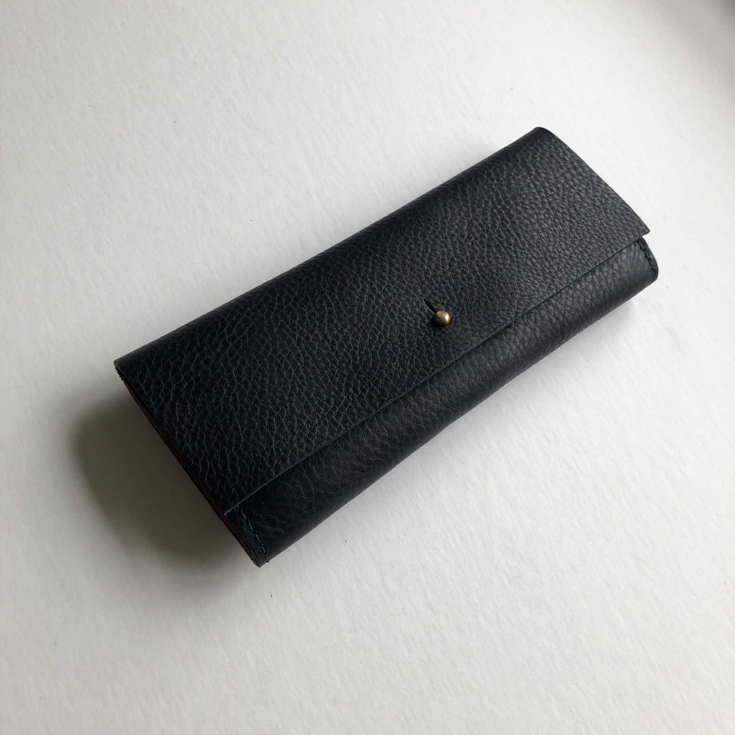 Nomad Midi Leather Folding Wallet in black with smooth brass press-stud closure, handcrafted from sustainable vegetable-tanned leather.