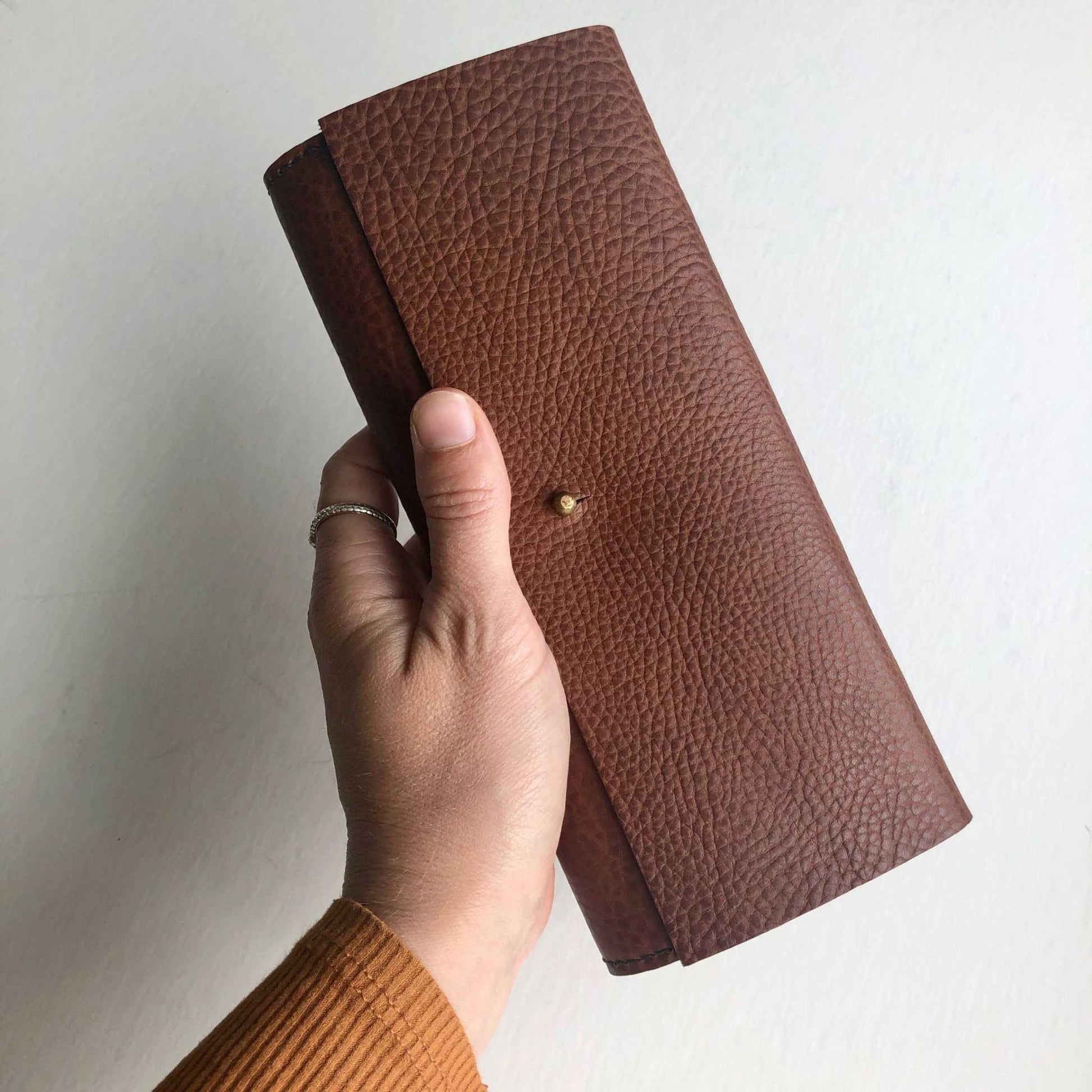 Nomad Maxi Leather Folding Wallet Purse in Tan held in hand.