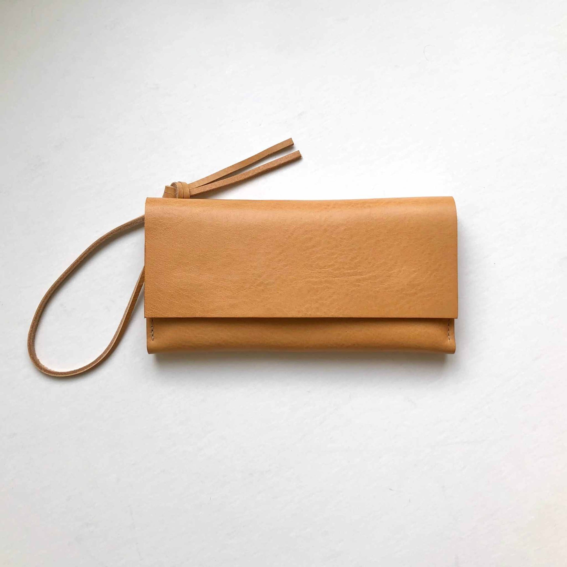 Knot Leather Purse Wallet in tan vegetable-tanned leather with optional wrist strap, minimalist design.