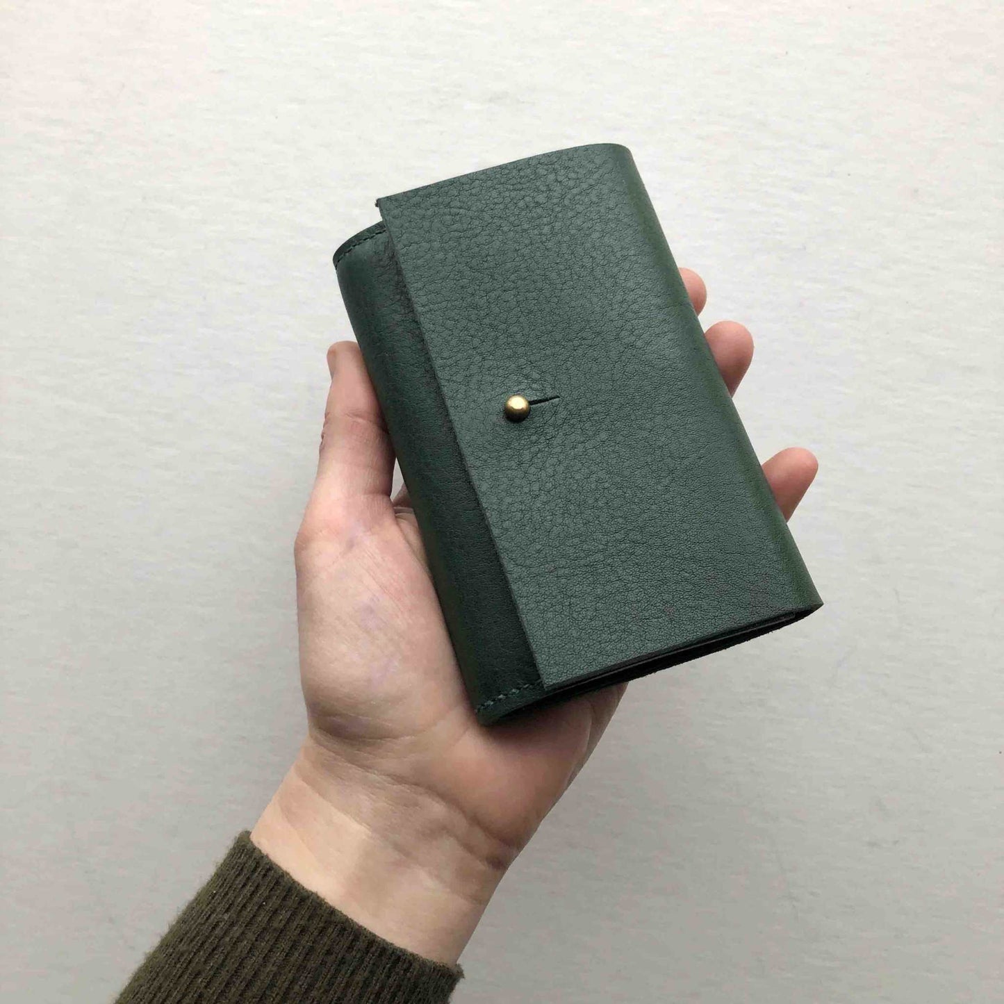 Nomad Mini Leather Women's Wallet in green displayed in hand.