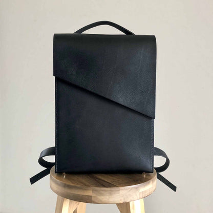 Pioneer Black Leather Backpack with minimalist design on a wooden stool.