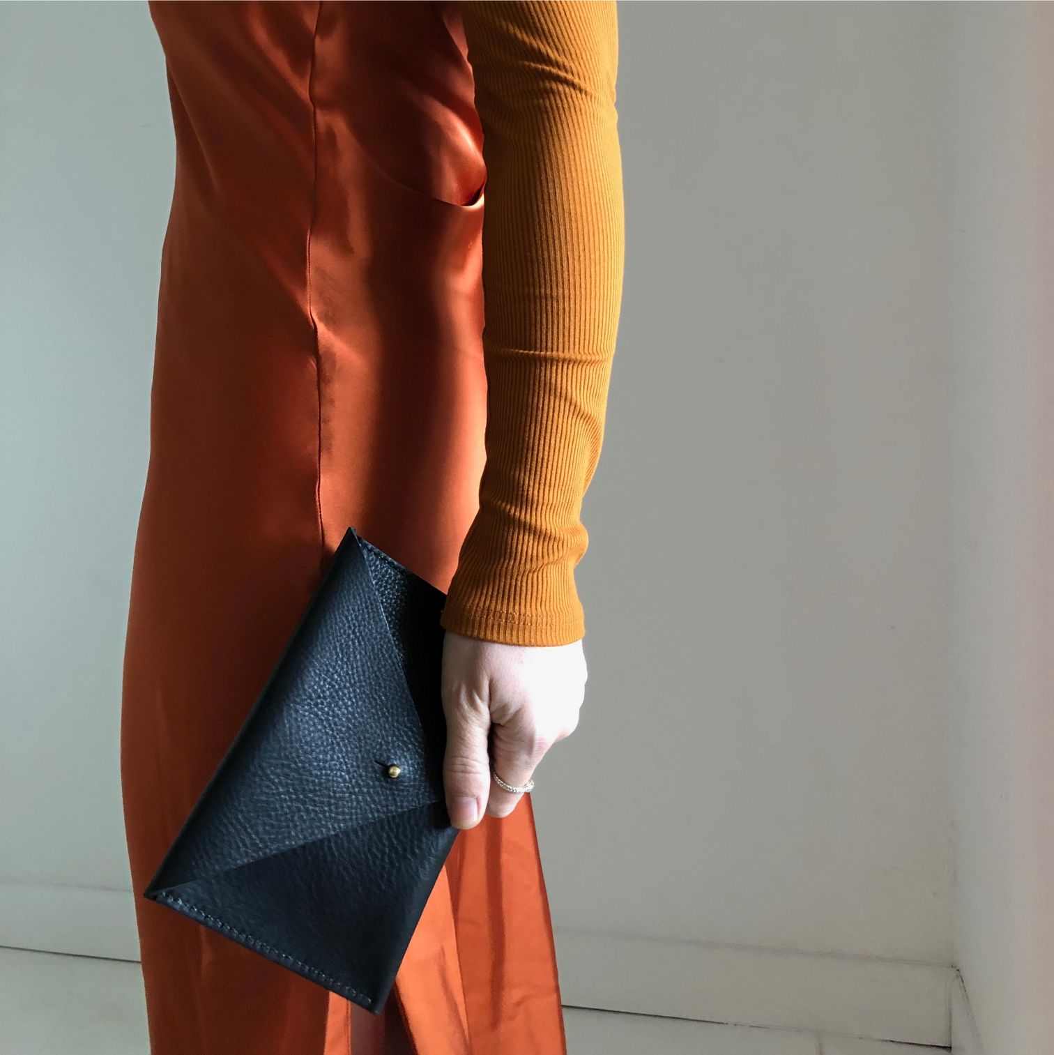 Drifter Maxi Leather Purse Wallet in black leather held by person in orange dress.