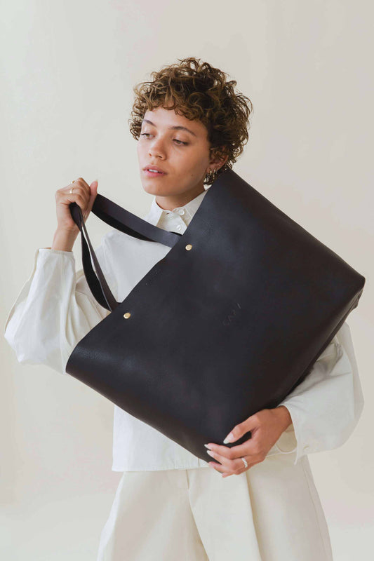 Basket Maxi Leather Tote Bag in black, worn by a person, showcasing its large capacity and minimalist design.