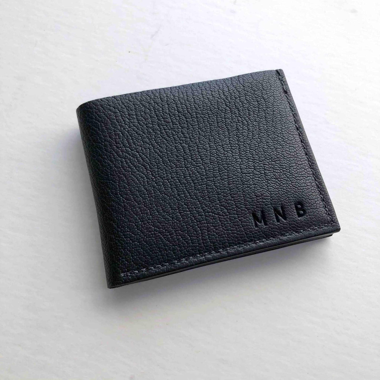 Handmade Black Leather Bifold Wallet crafted in England, sustainable vegetable-tanned leather, minimalist design.