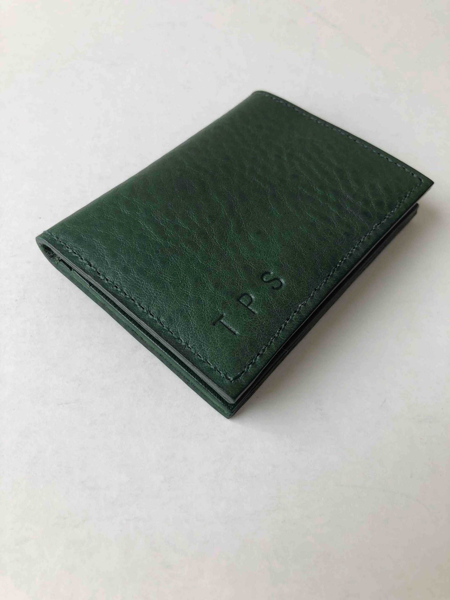 Personalised green leather card wallet with embossed initials, handcrafted from forest green pebble leather.