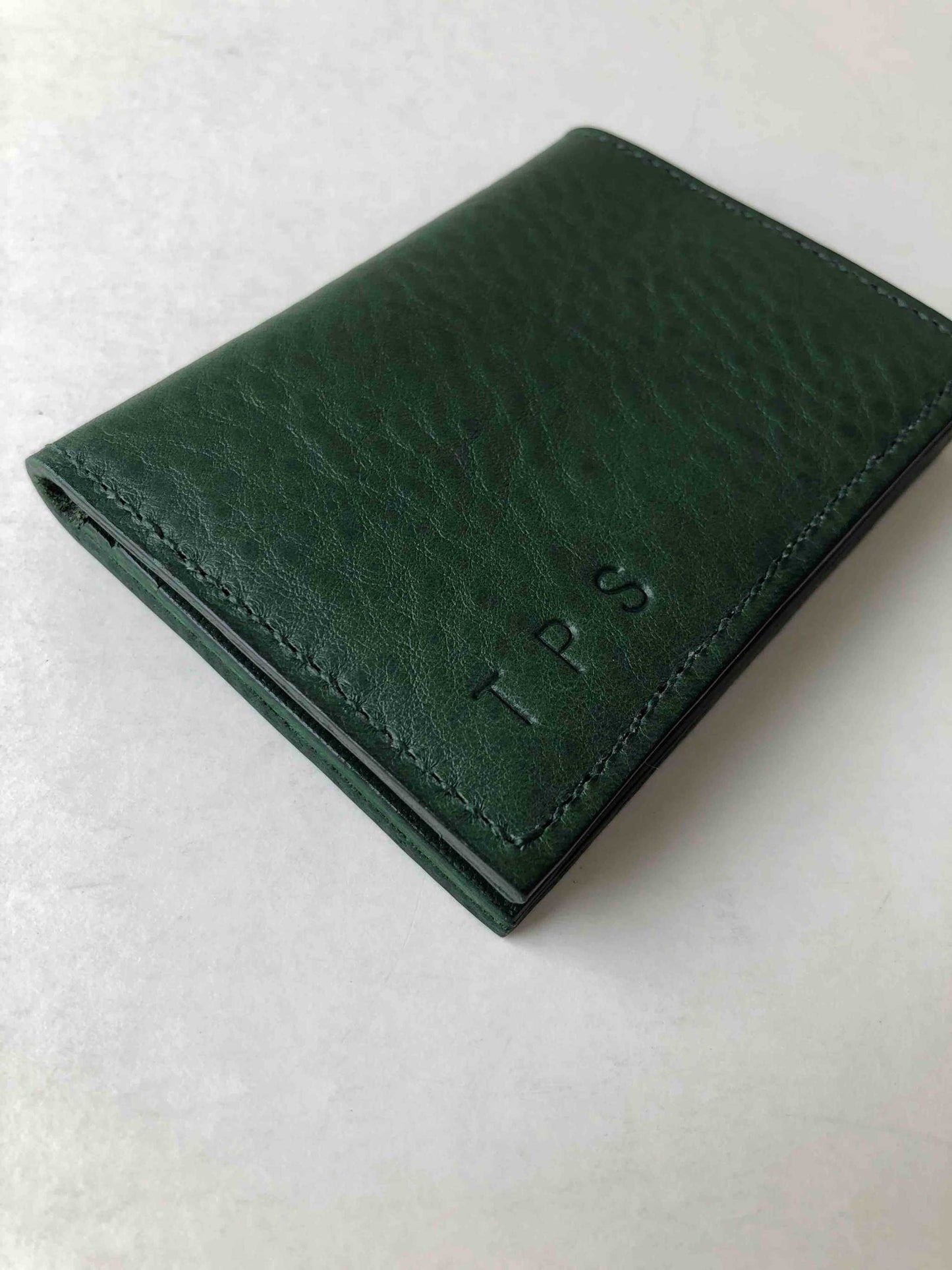 Personalised green leather card wallet with embossed initials, handcrafted in the UK.