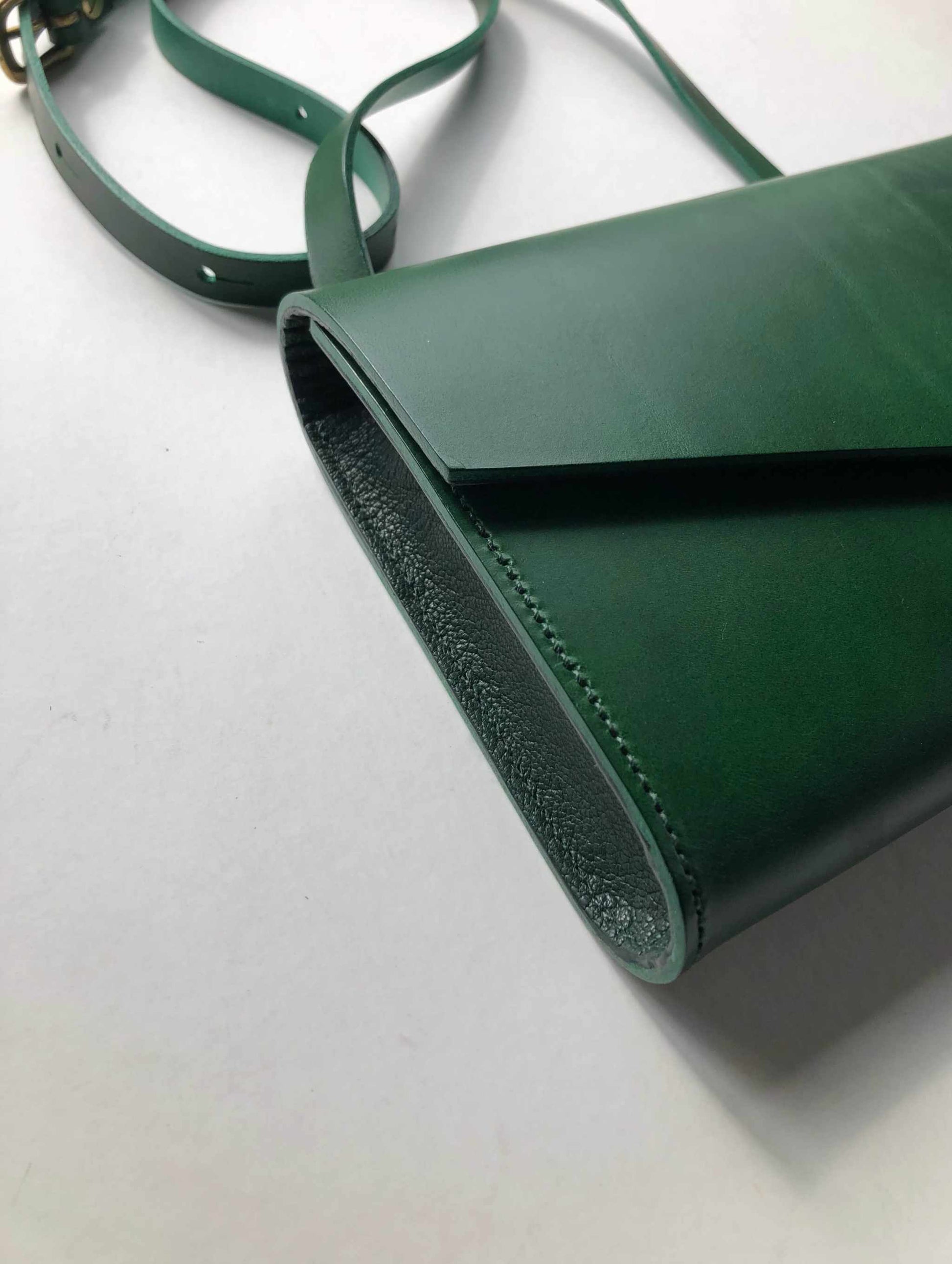 Mini green leather crossbody bag with adjustable strap made from sustainable vegetable-tanned leather.