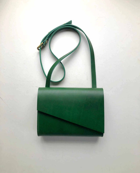 Green leather crossbody bag with adjustable strap and minimalist design.