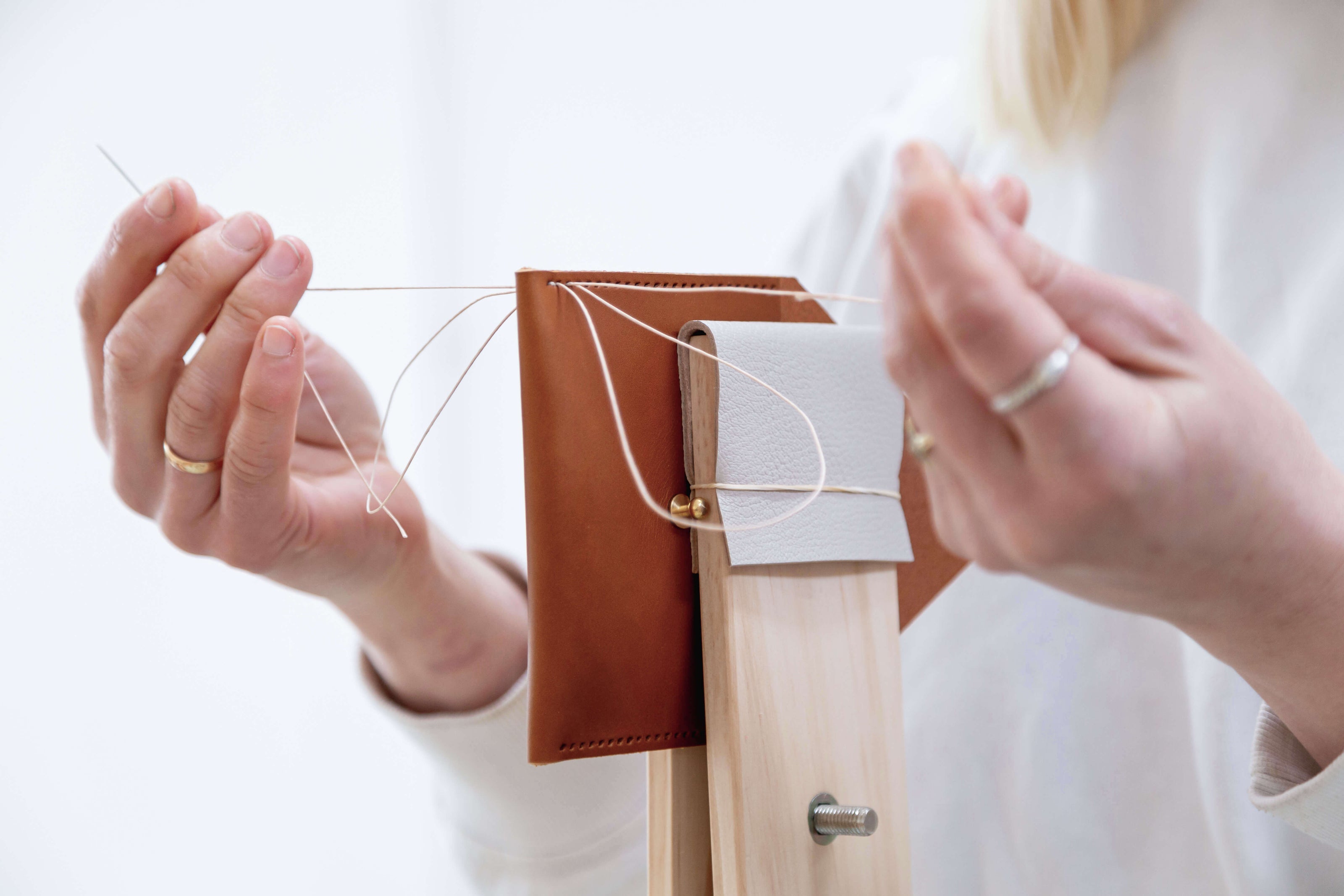 Hands stitching a leather purse