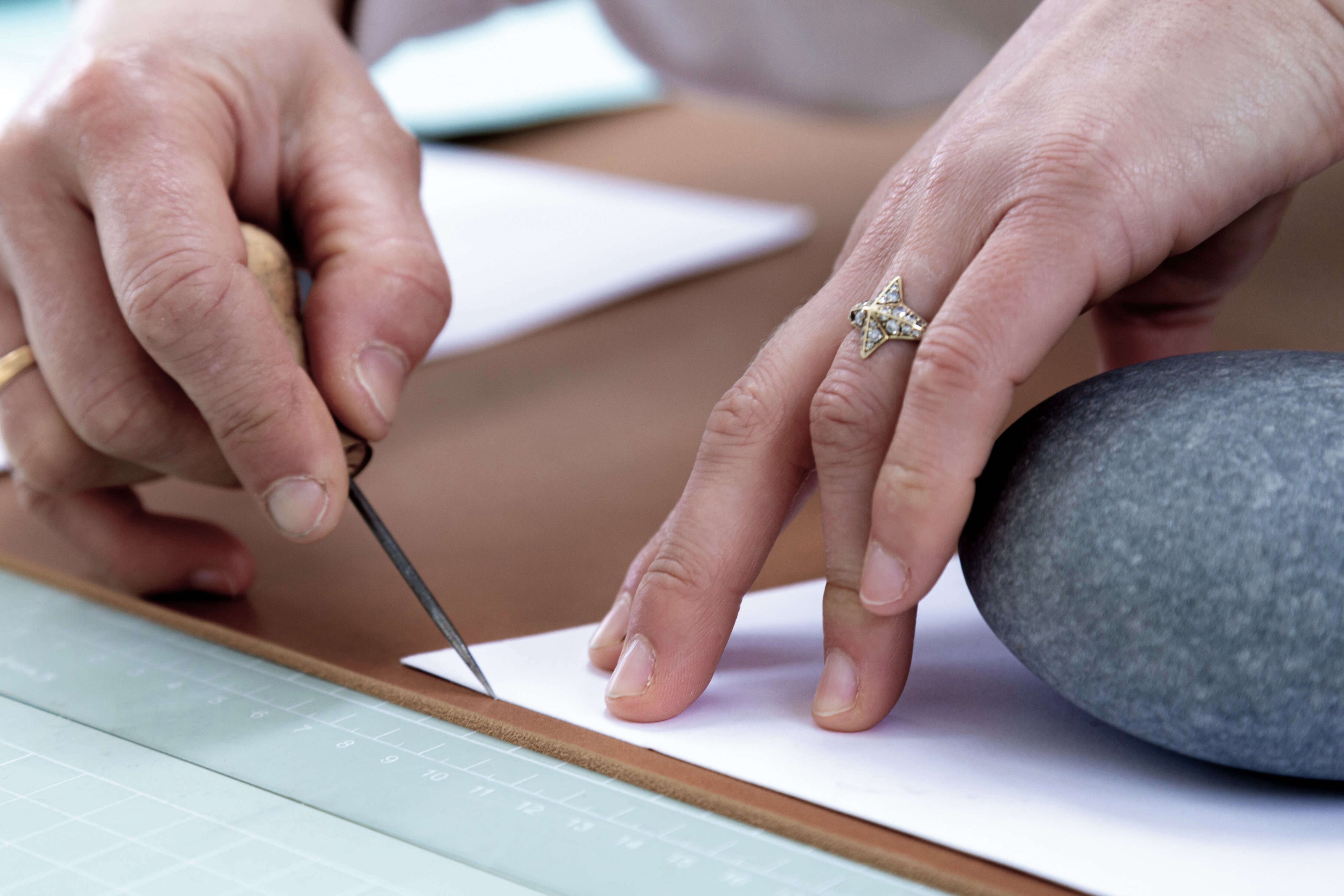 Hands using leather scratch awl to mark leather