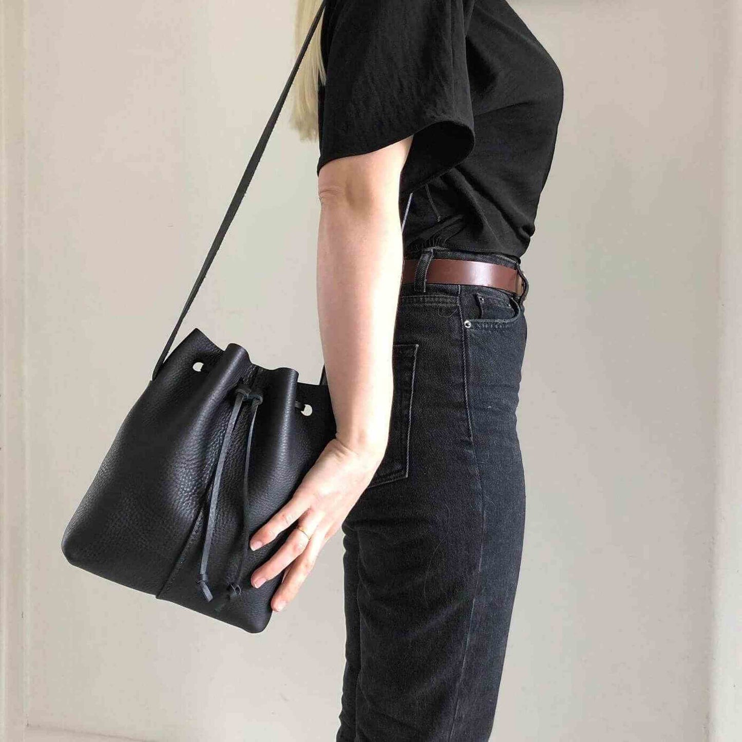 Nomad Mini Leather Bucket Bag in black, worn crossbody by model in black jeans and t-shirt.