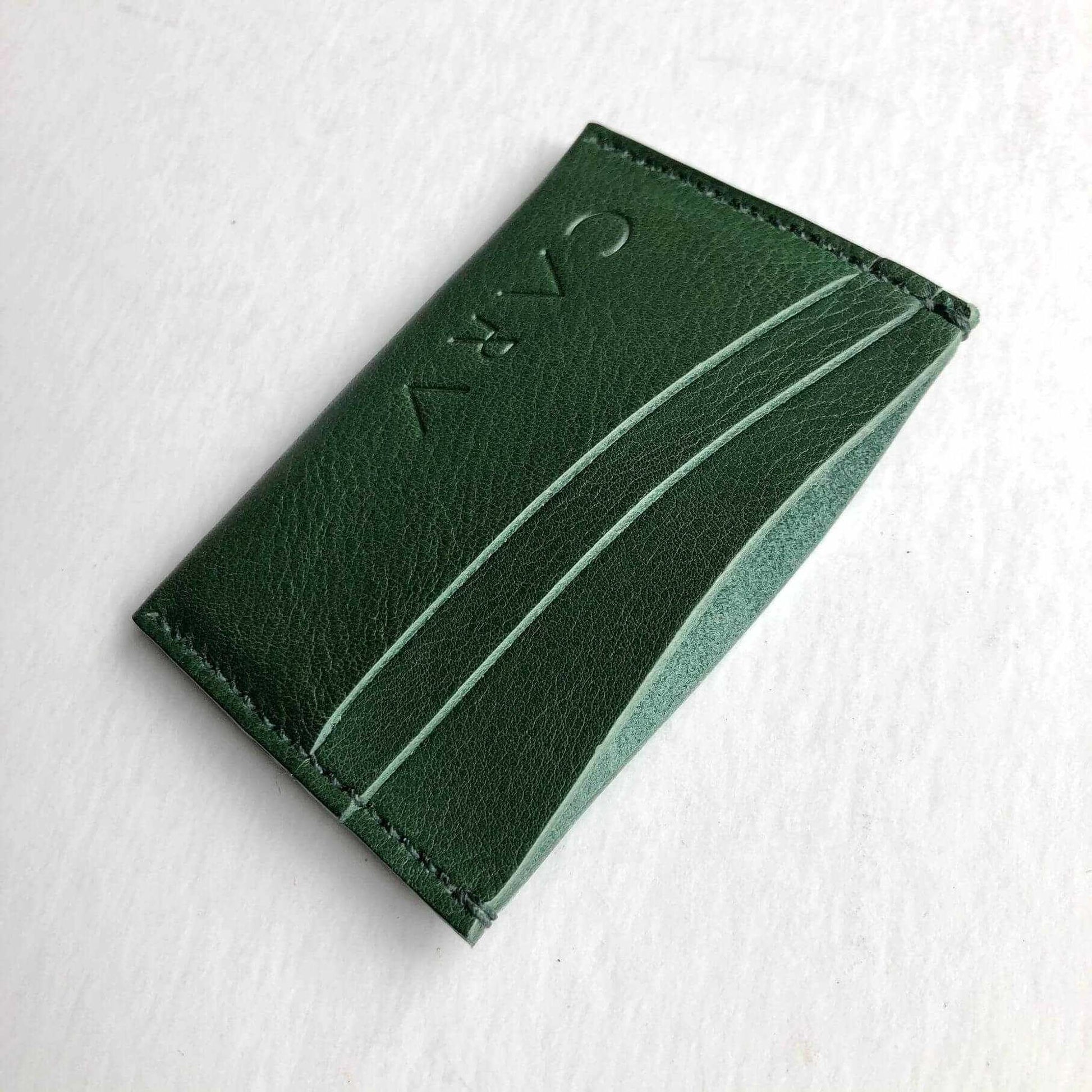 Green leather card holder with sleek bifold design and embossed CARV logo.