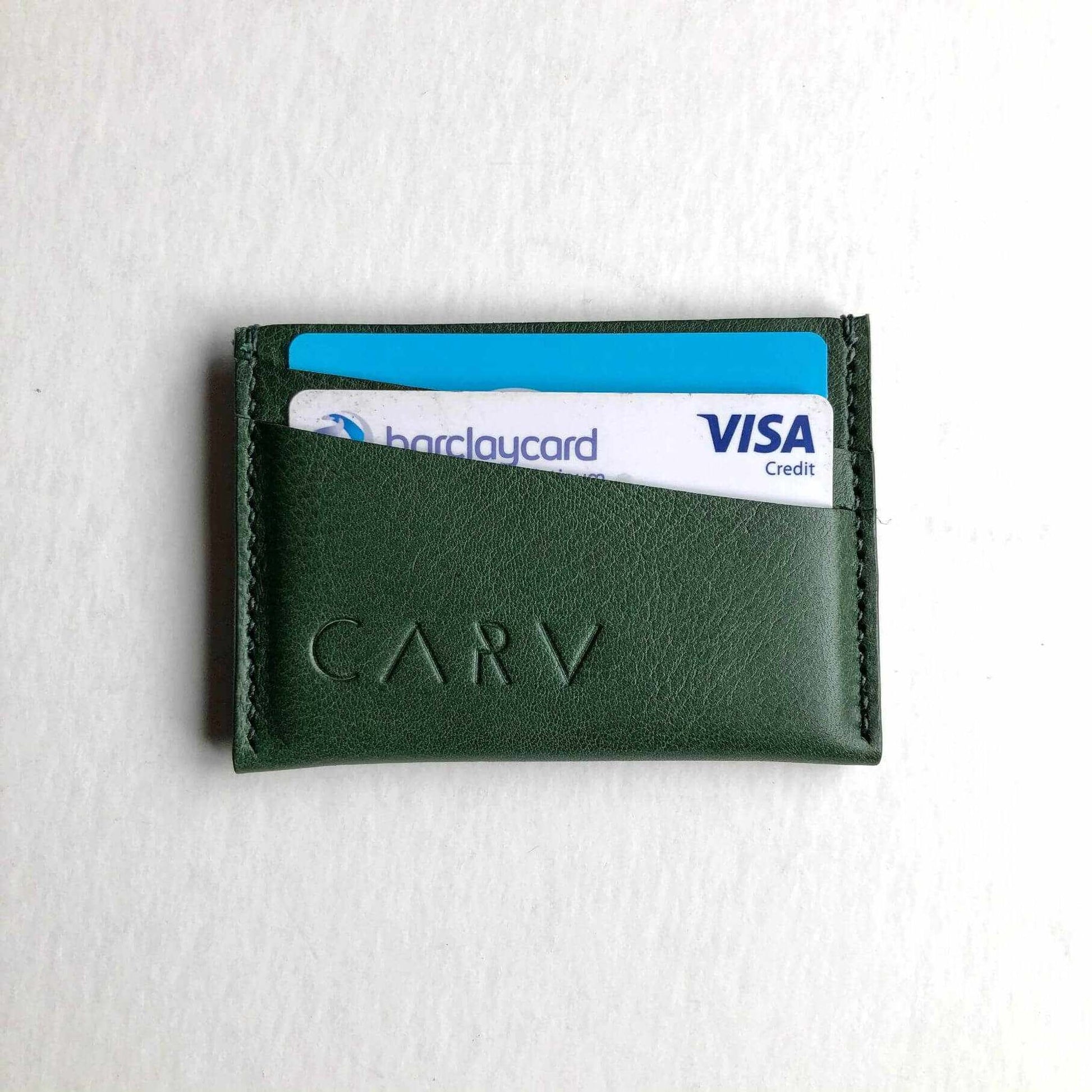 Green leather card holder with two card slots, minimalist design.