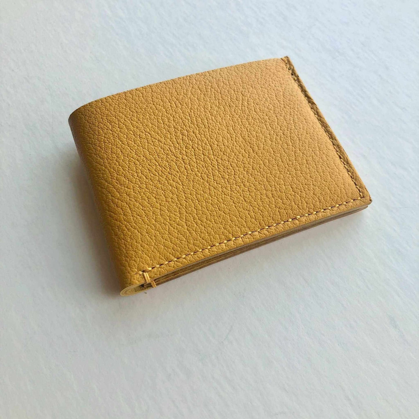 Mustard yellow handmade leather wallet with minimalist design and card slots.