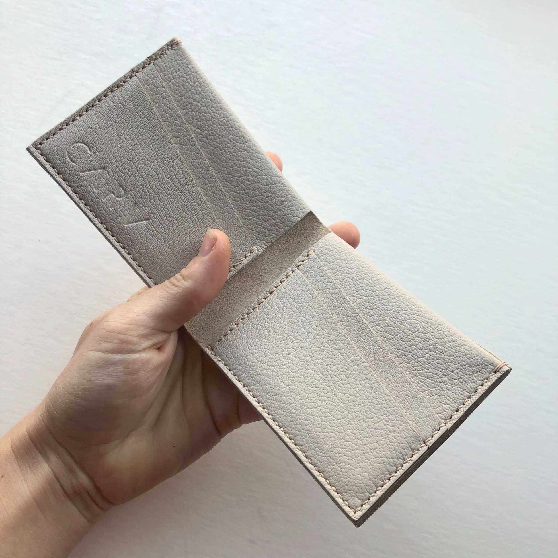 Handmade leather wallet in taupe grey, bifold style with card slots, sustainable UK craftsmanship.