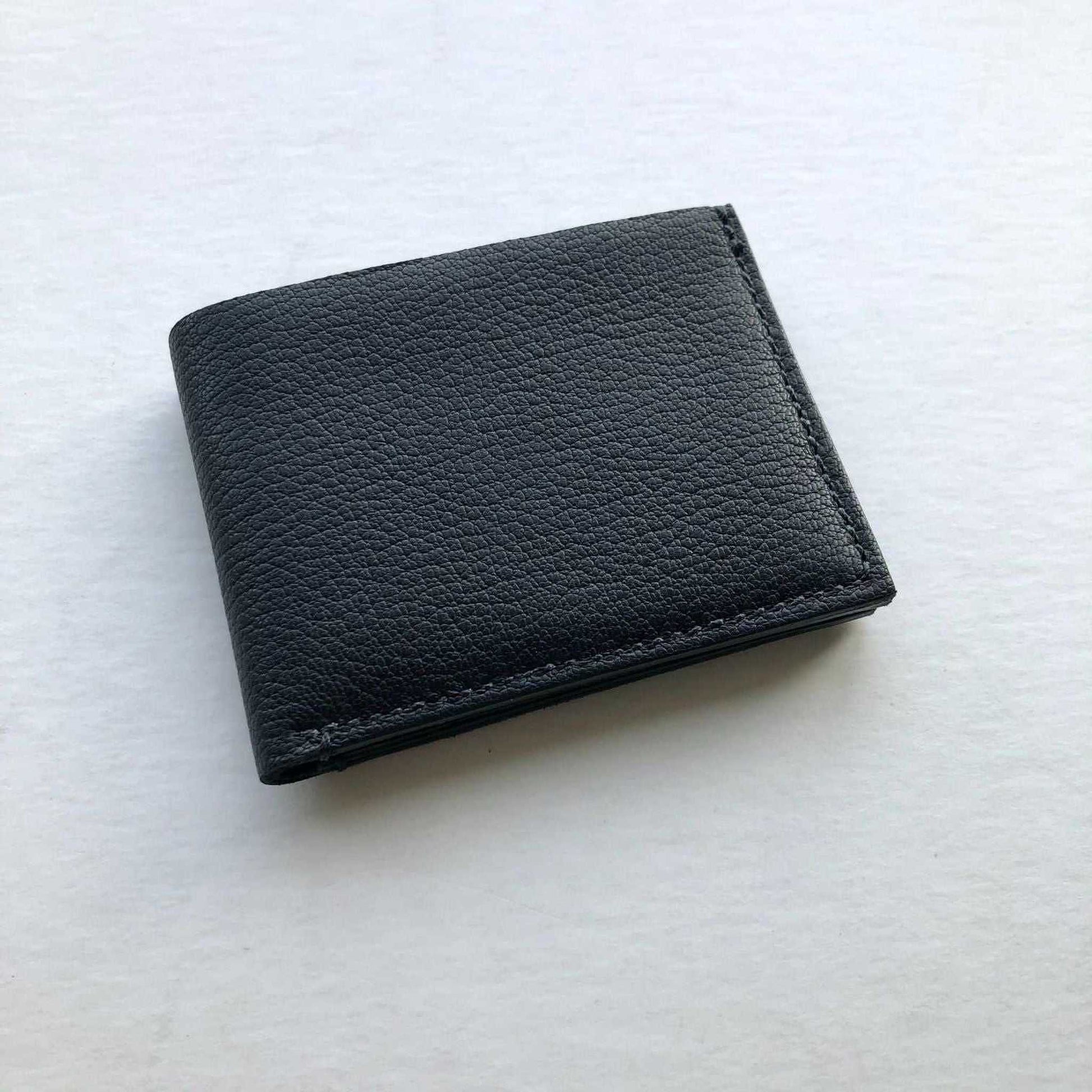 Handmade black leather bifold wallet crafted in England, minimalist design.