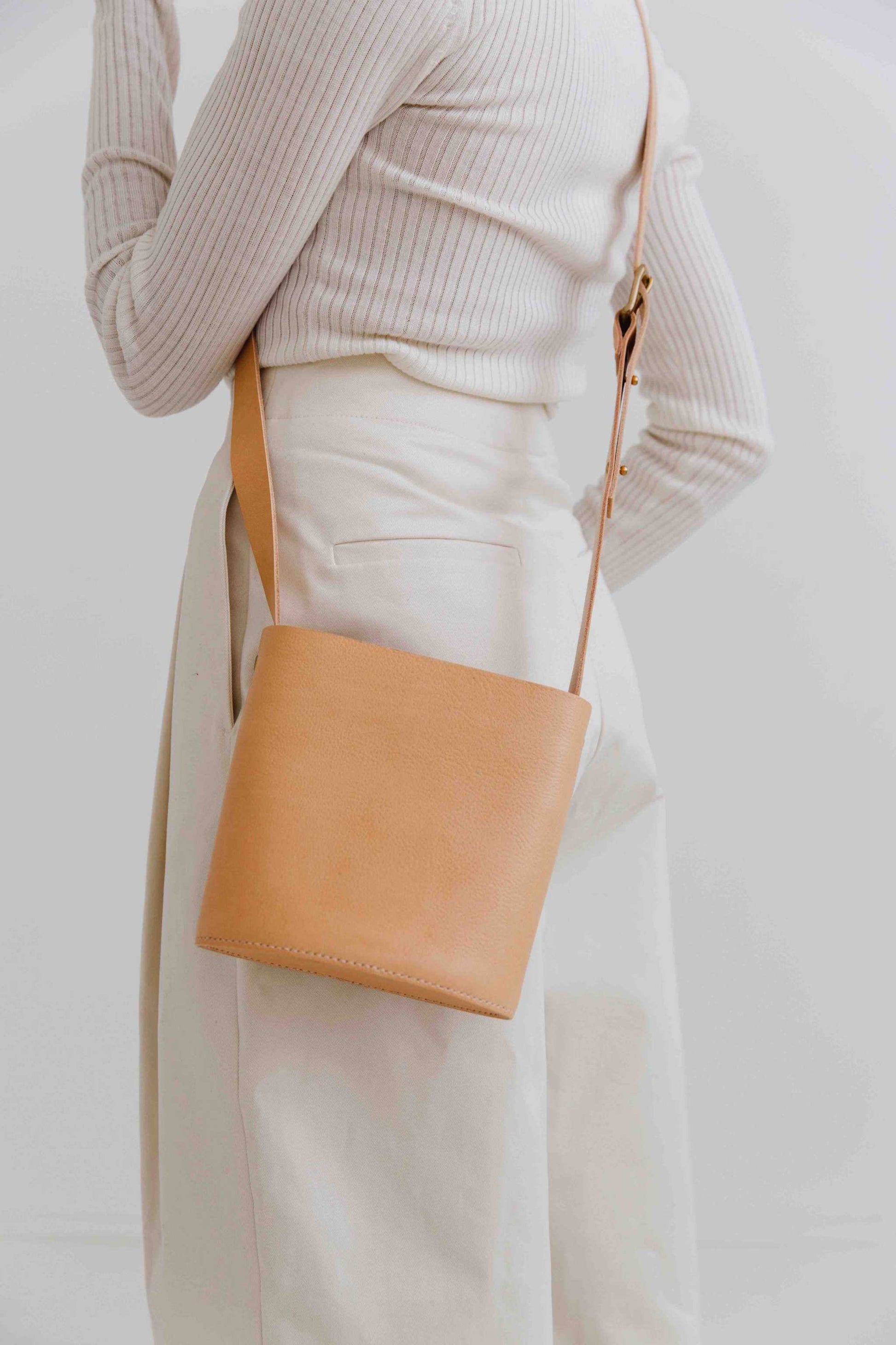 Oval Mini Leather Bag with adjustable strap, worn crossbody by model in neutral outfit.