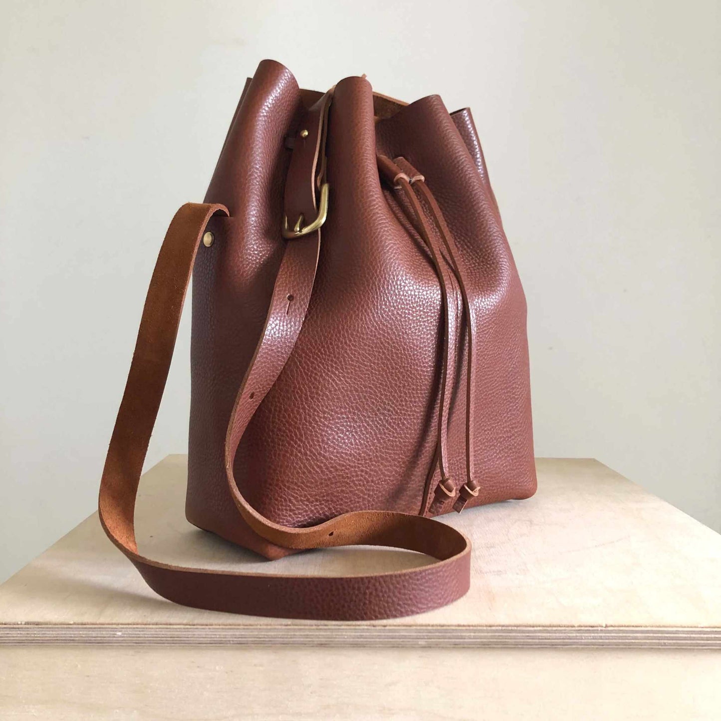 Nomad Maxi Leather Bucket Bag in tan leather with adjustable shoulder strap, spacious interior, and sustainable craftsmanship.