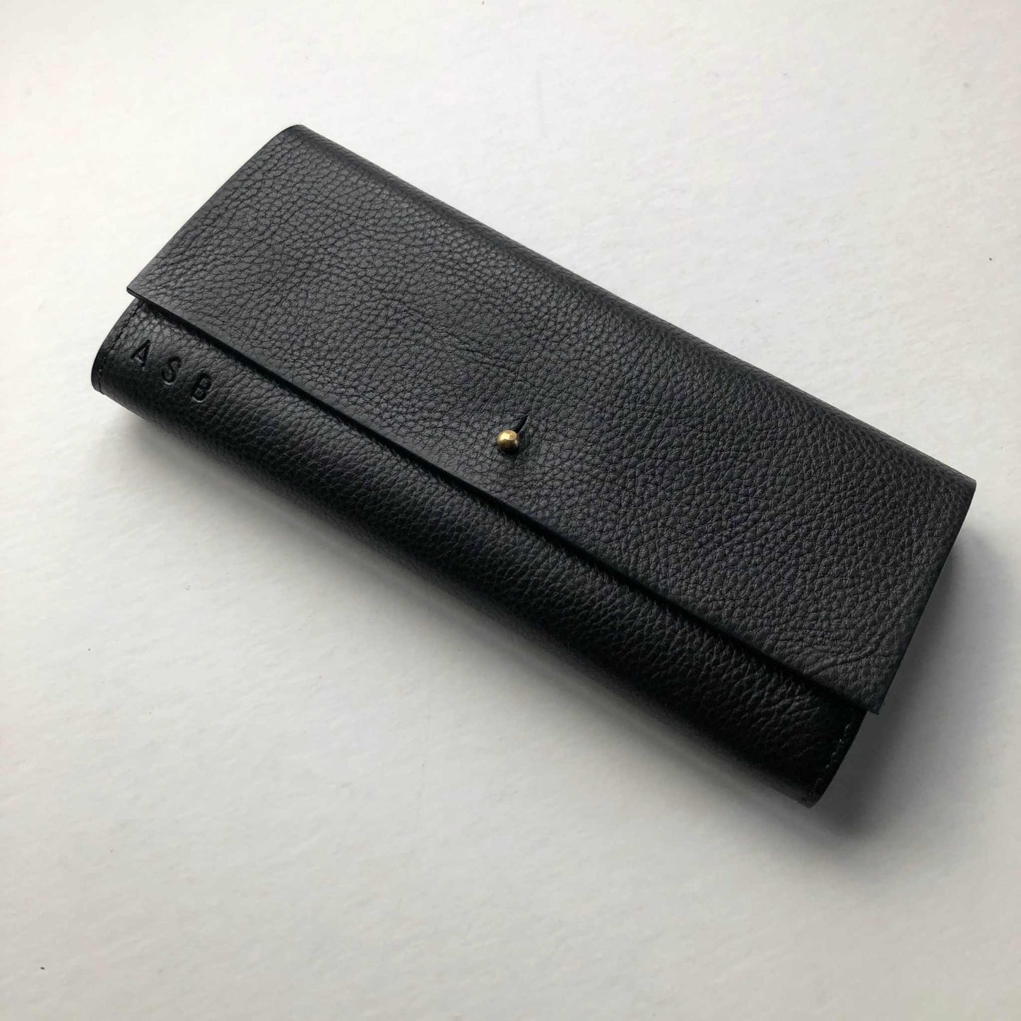 Nomad Maxi Leather Folding Wallet Purse in black, featuring a solid brass press stud and personalization option.