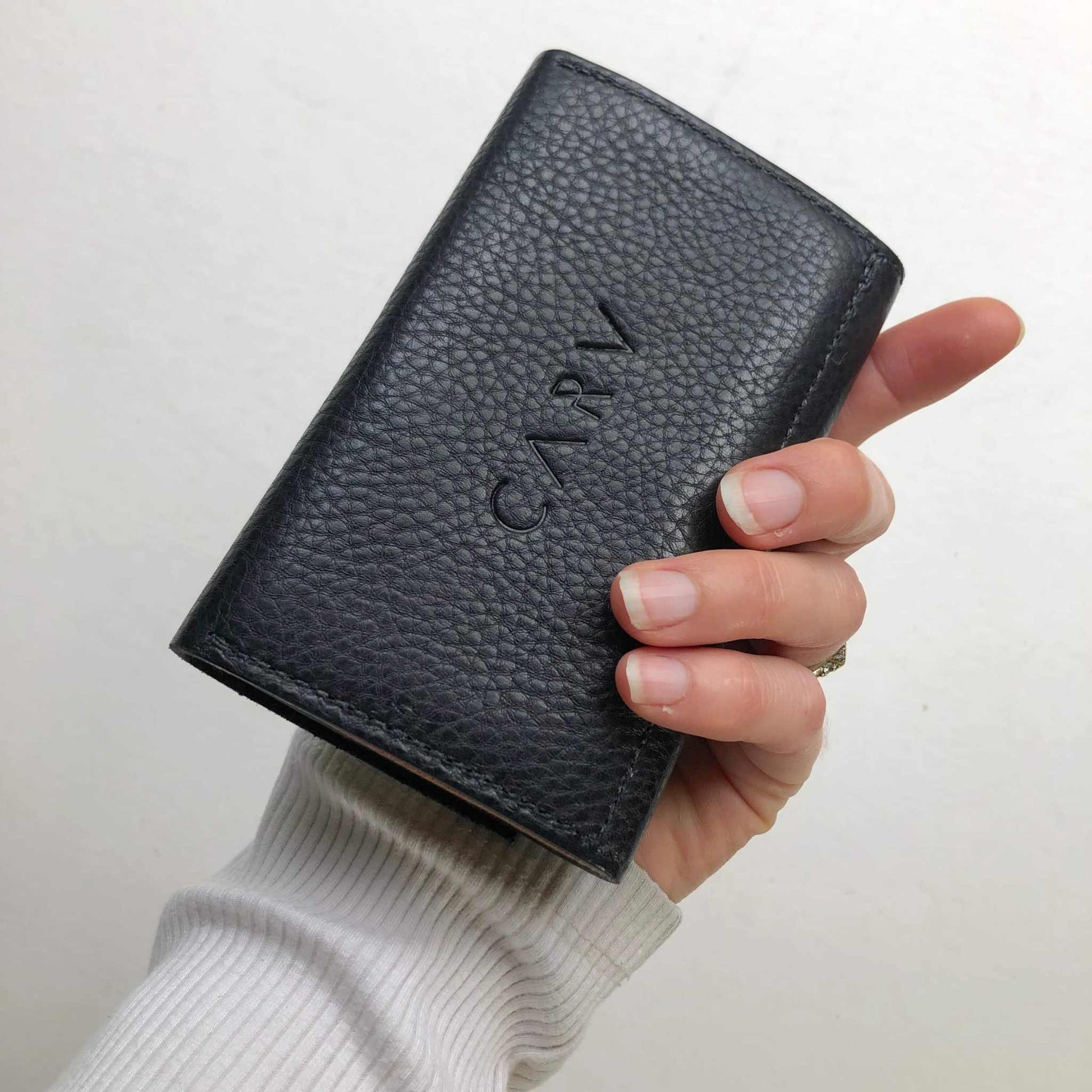 Nomad Mini Handmade Leather Wallet in black, pebbled texture with hand holding it.