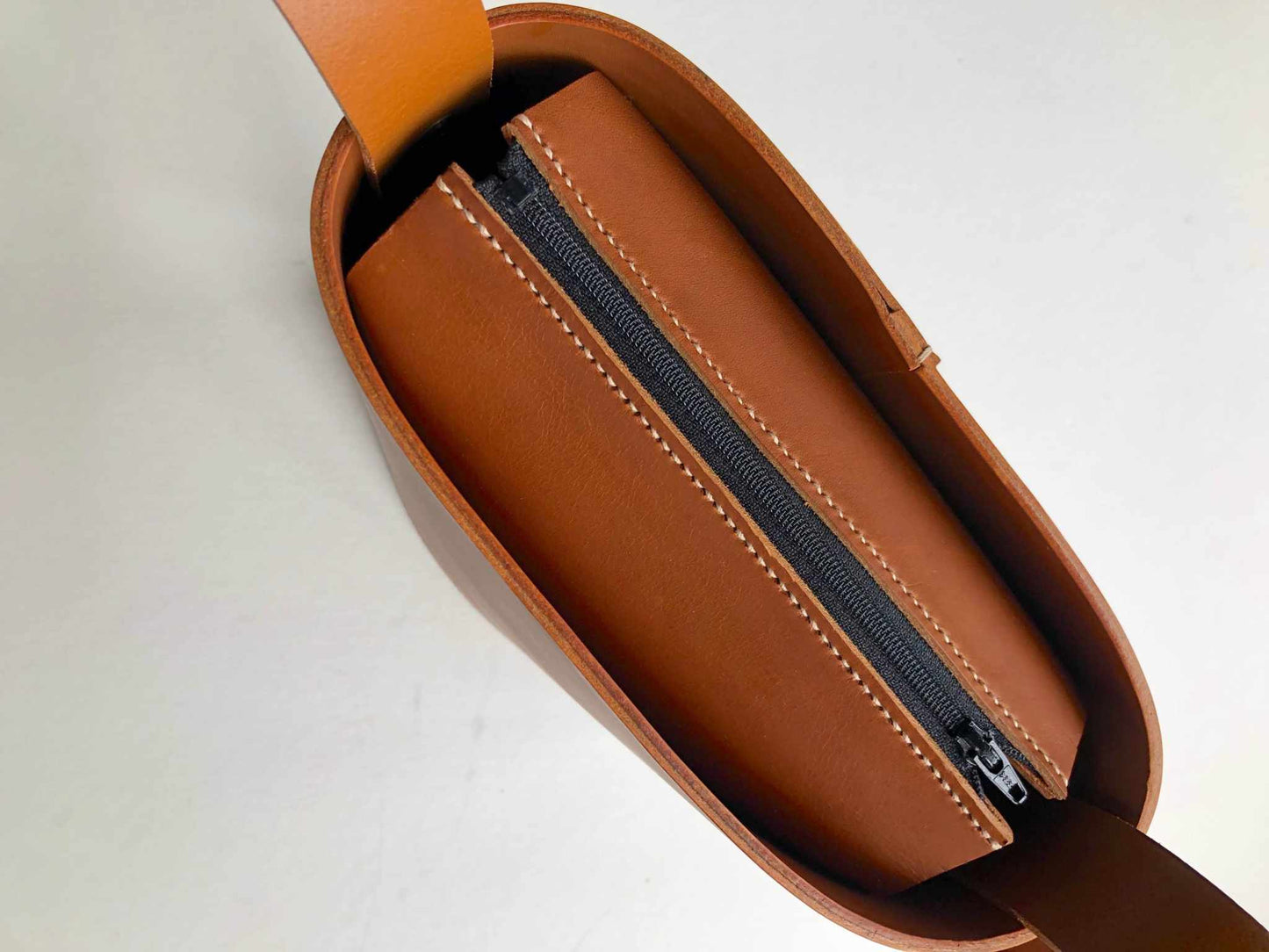 Top view of the Oval Midi Leather Bag in tan, showcasing its zip closure and luxurious vegetable-tanned leather finish.