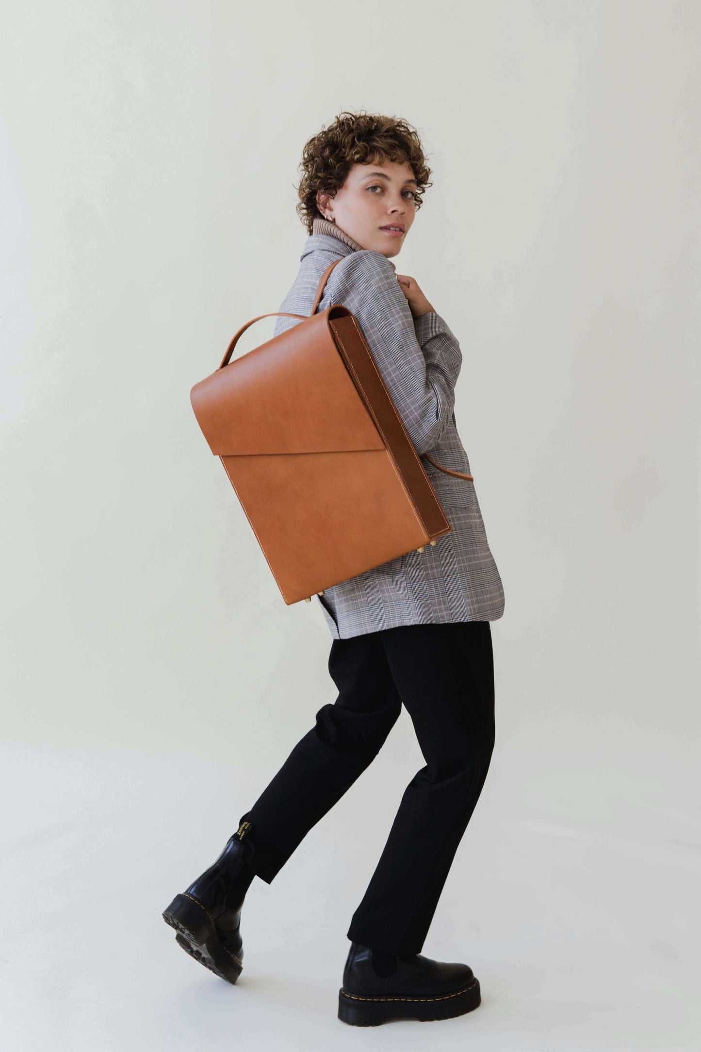 Pioneer Tan Leather Backpack stylishly worn by model in gray blazer and black pants.