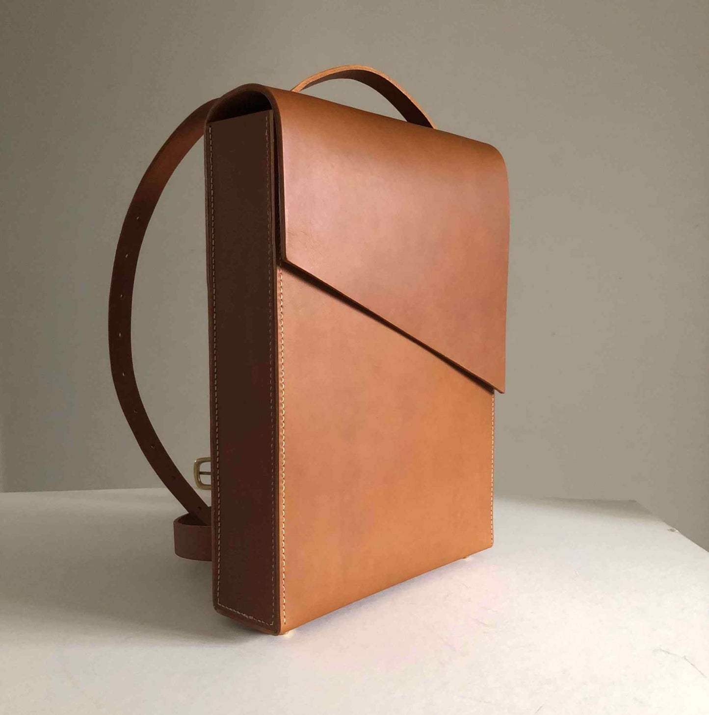 Minimalist Pioneer Tan Leather Backpack with adjustable straps and sleek design.