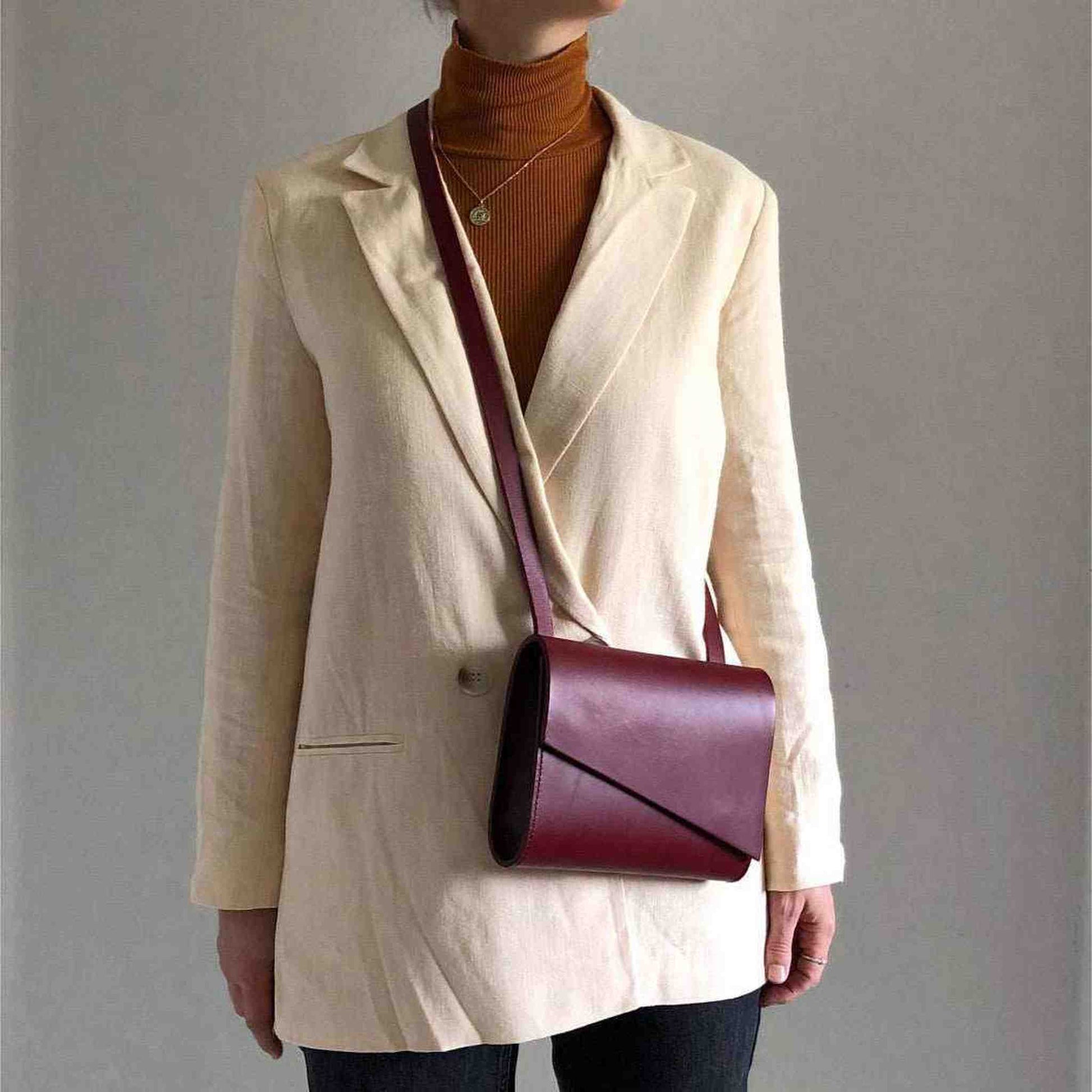 Red leather crossbody bag worn by woman in white blazer.