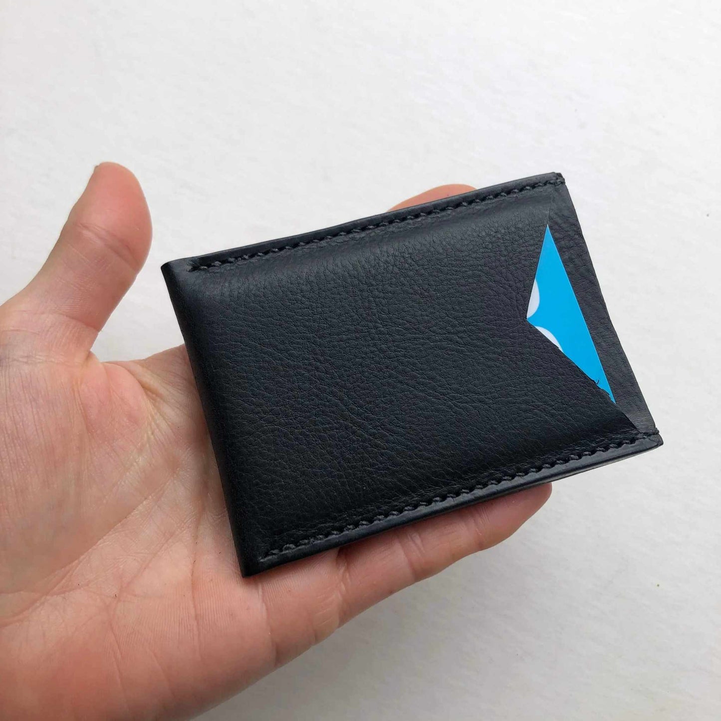 Nomad Leather Card Wallet Sleeve in black leather, held in hand, showcasing its minimalist design and compact size.