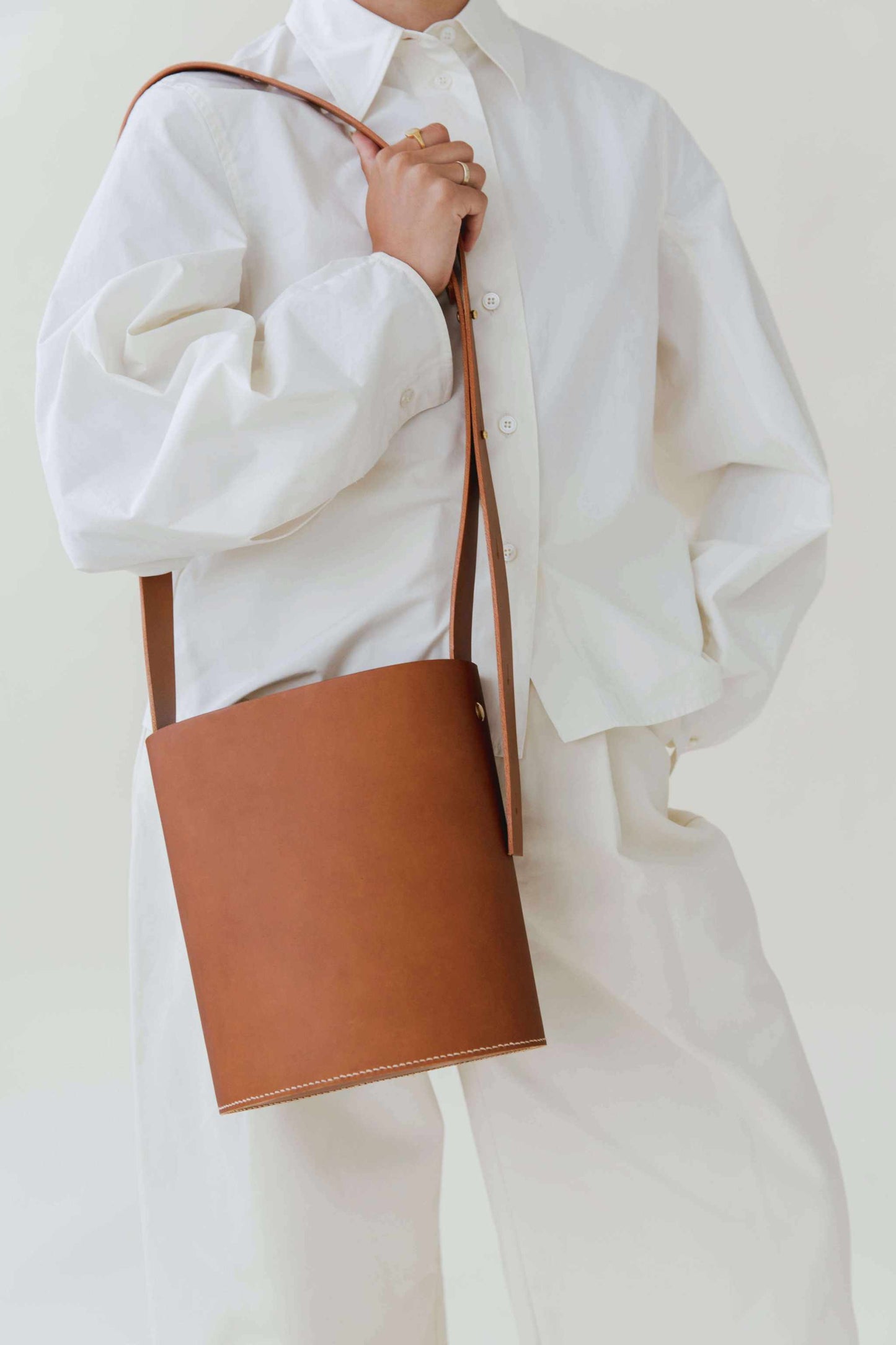 Oval Midi Leather Bag in tan, worn with adjustable strap, minimalist design.