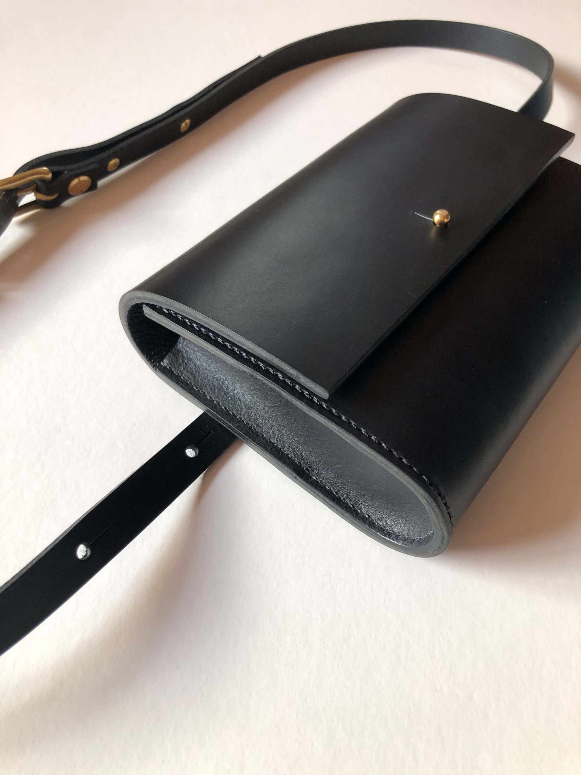 Sedna Black Leather Bum Bag with adjustable strap and brass clasp, minimalist design.