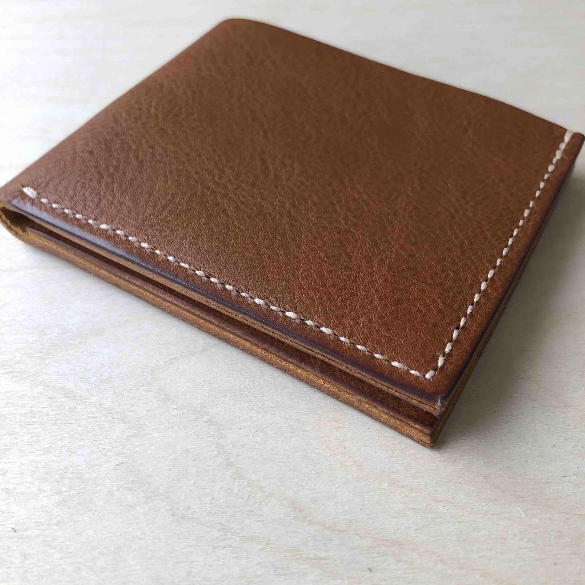 Handmade tan leather wallet displaying elegant craftsmanship and minimalist design.