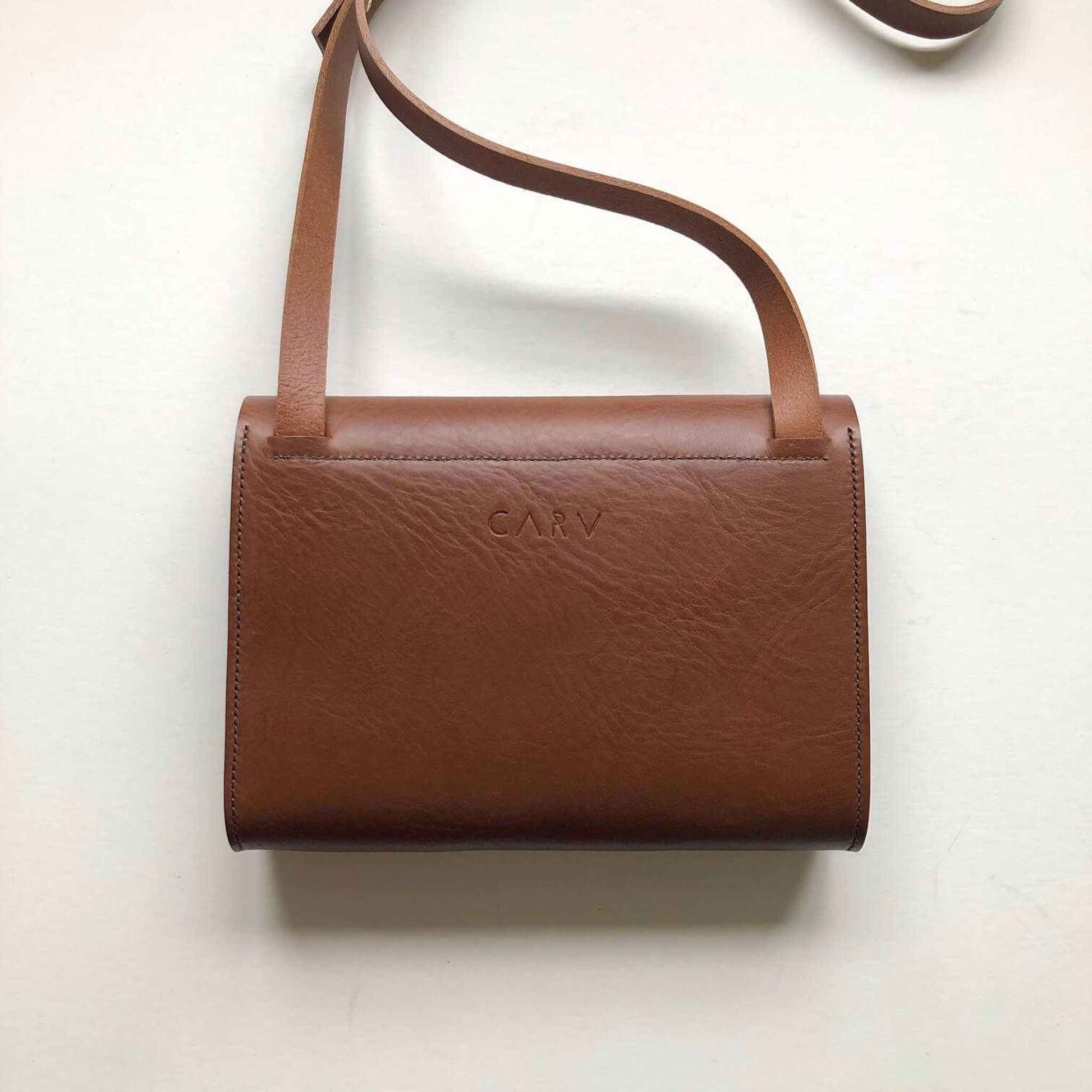 Tan leather crossbody bag with adjustable strap and minimalist design.