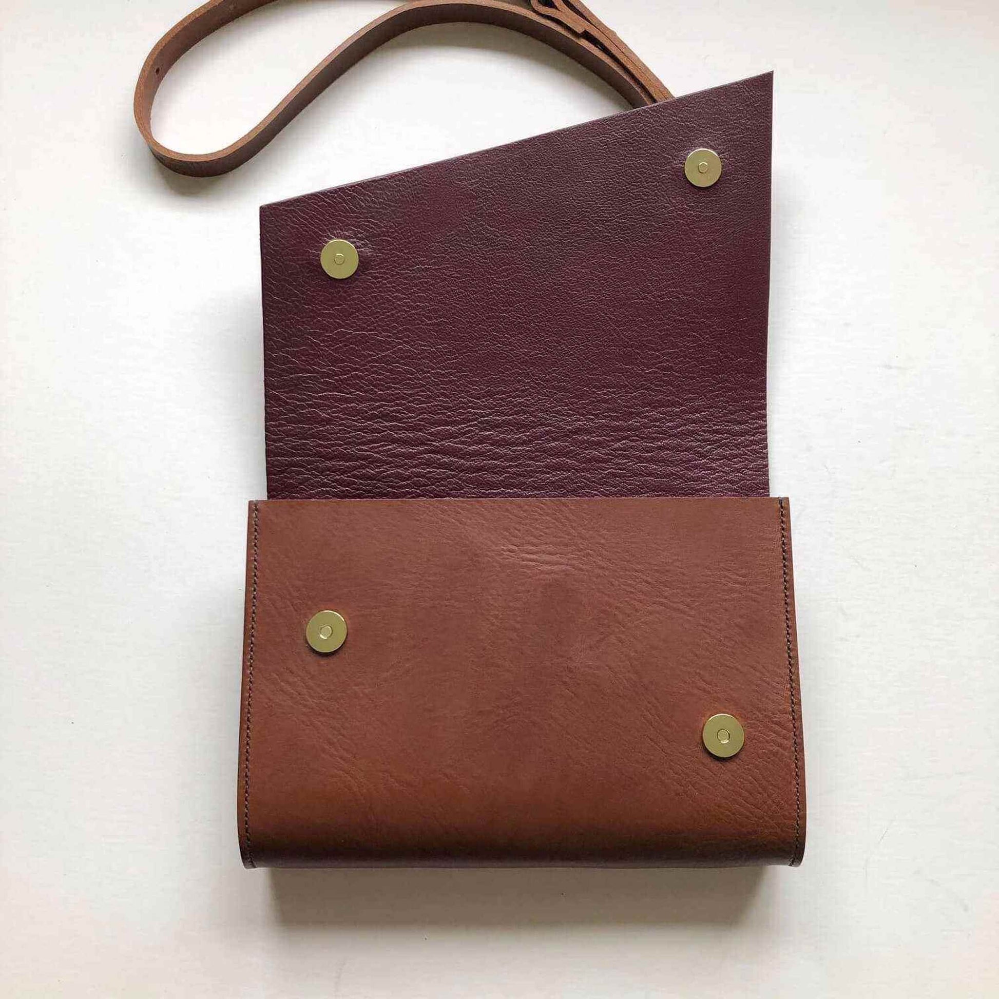 Tan leather crossbody bag with asymmetrical flap and brass buckle, handcrafted by CARV from sustainable vegetable-tanned leather.