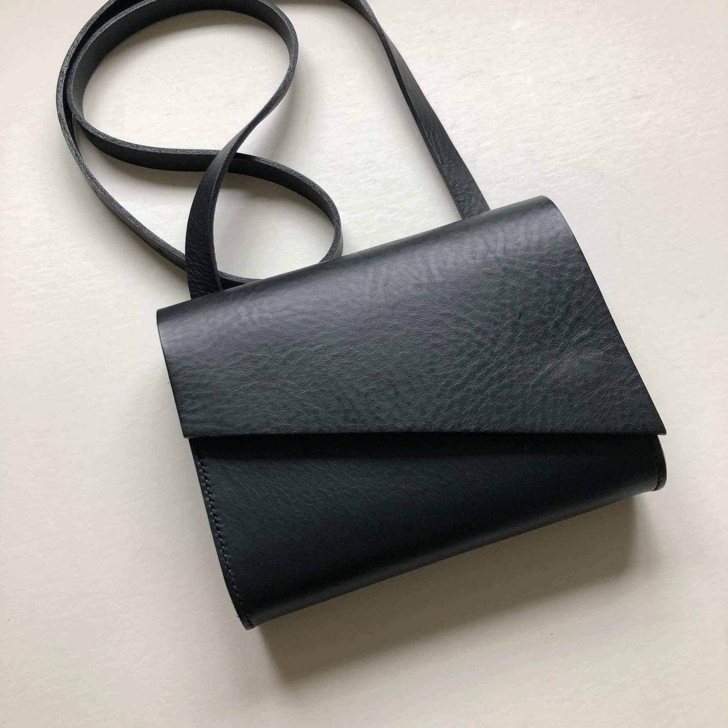 Pioneer Mini Black Leather Crossbody Bag with adjustable strap, crafted from sustainable leather.