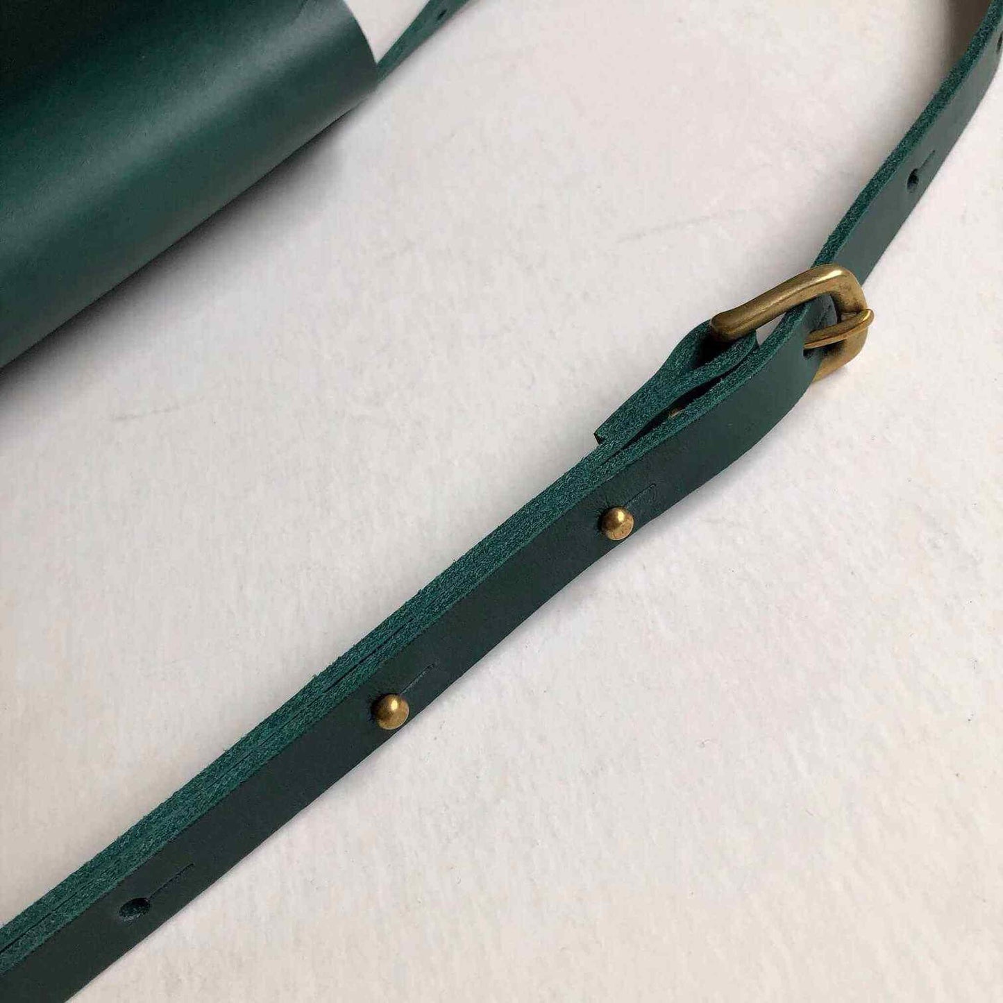 Green leather belt bag with adjustable strap and brass buckle, handcrafted from sustainable, vegetable-tanned leather.