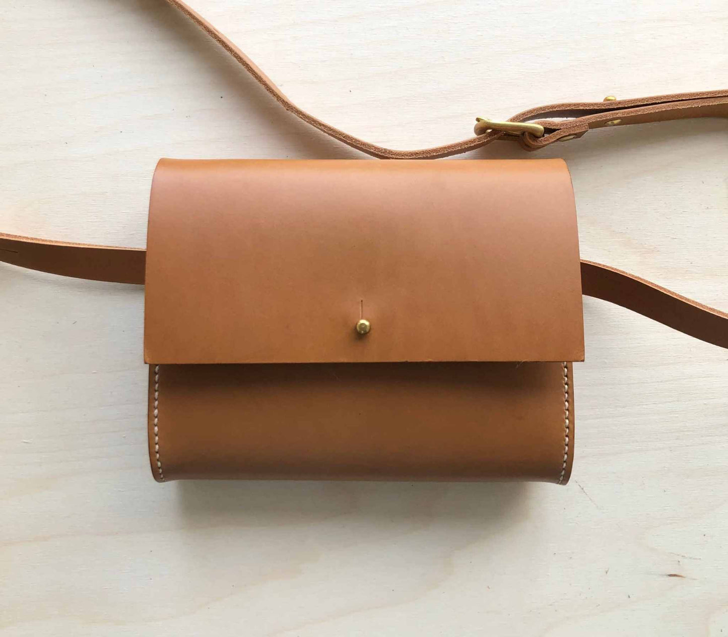 Tan Leather Belt Bag with a minimalist design, handcrafted in the UK from vegetable-tanned leather, featuring a structured silhouette and versatile carrying options.