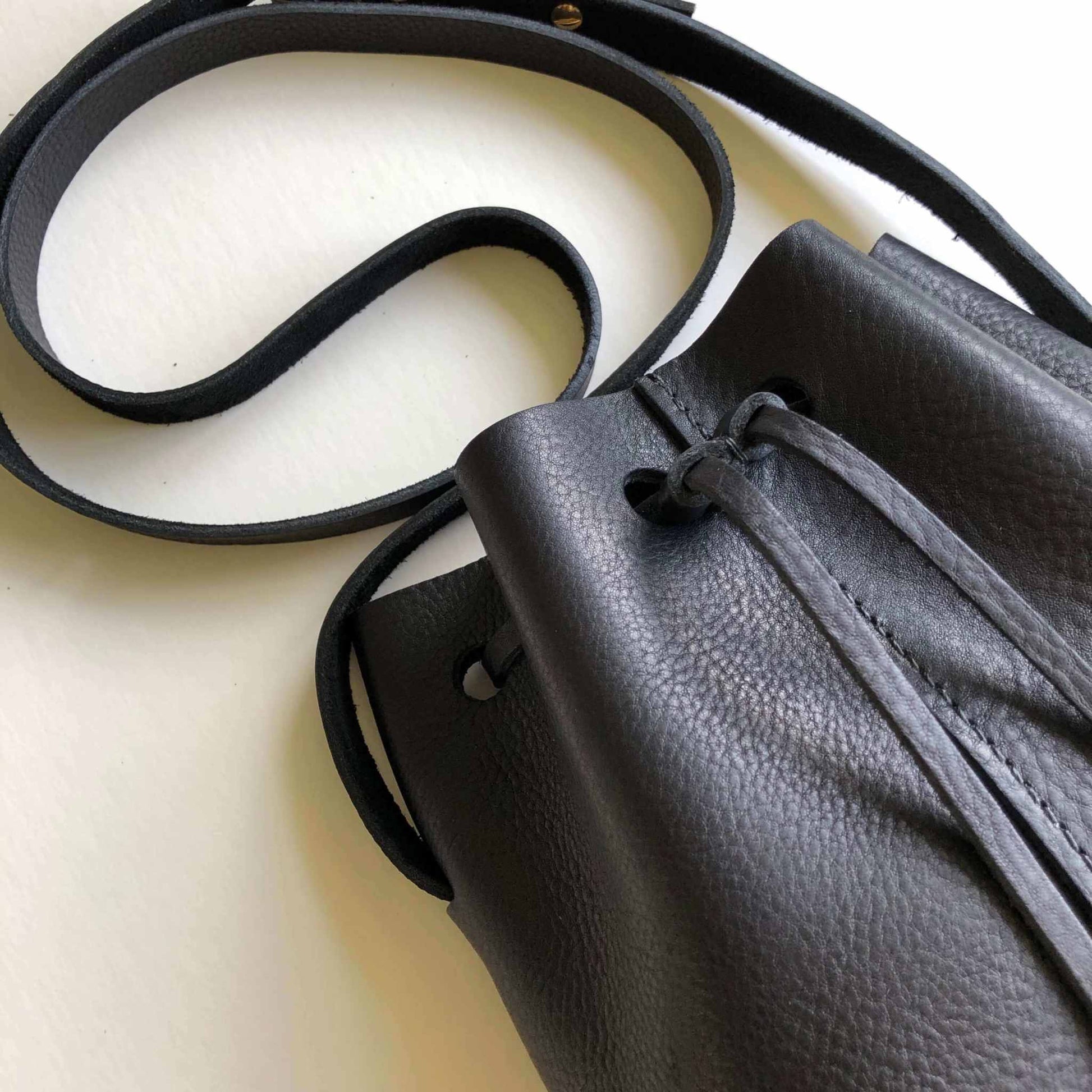 Nomad Mini Leather Bucket Bag in black, handcrafted with raised grain texture and adjustable strap.