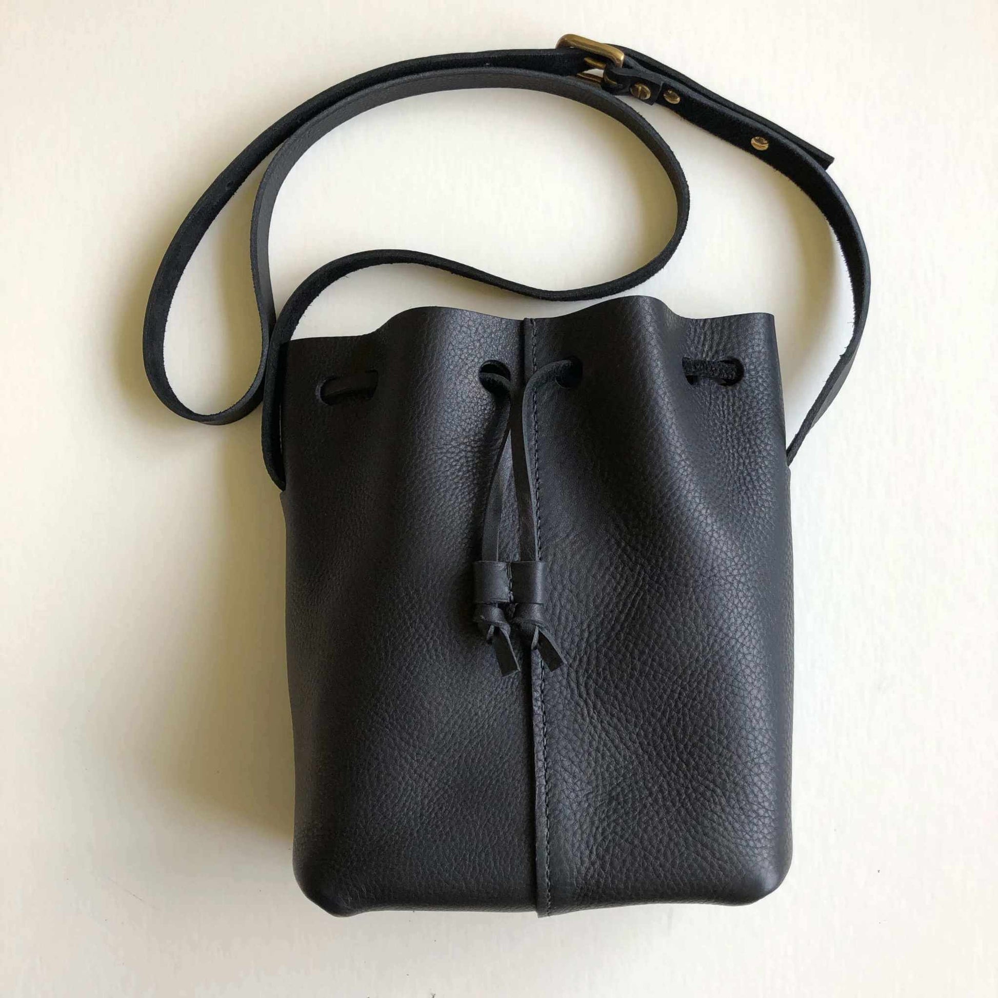 Nomad Mini Leather Bucket Bag in black with adjustable strap and drawstring closure.