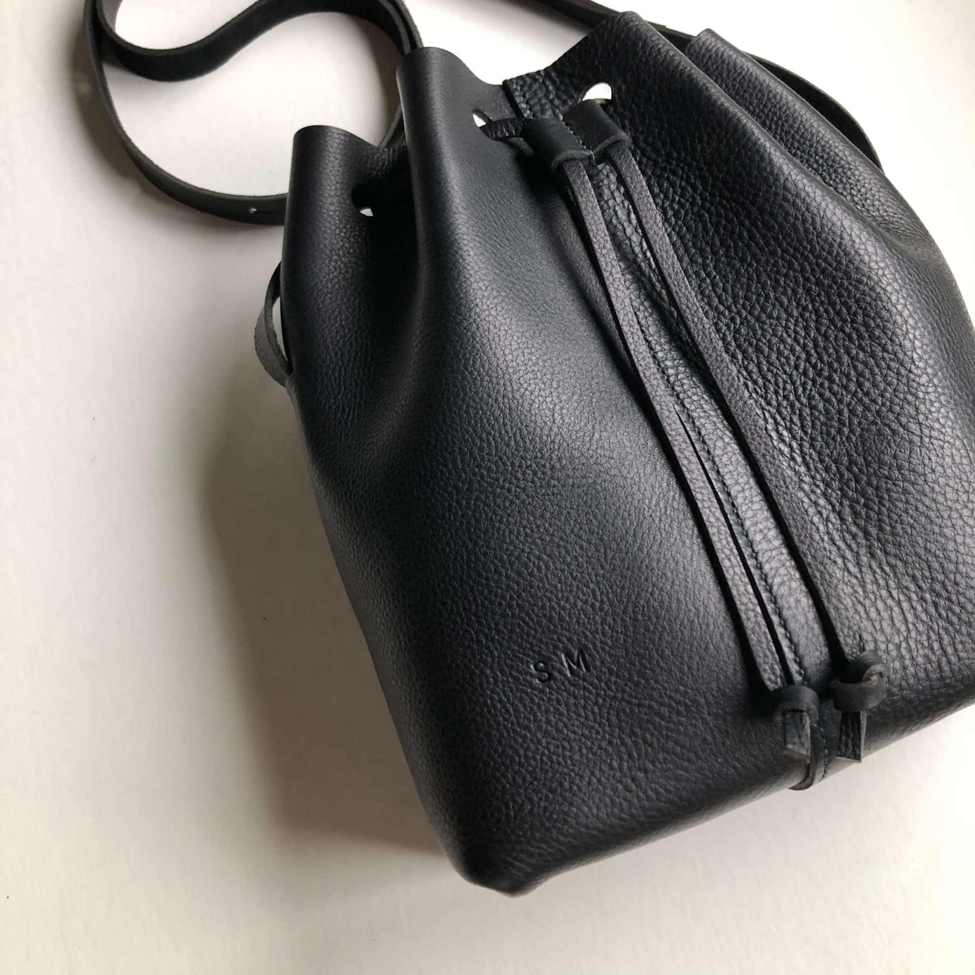 Nomad Midi Black Leather Bucket Bag by CARV with drawstring style, adjustable strap, and durable vegetable-tanned leather.