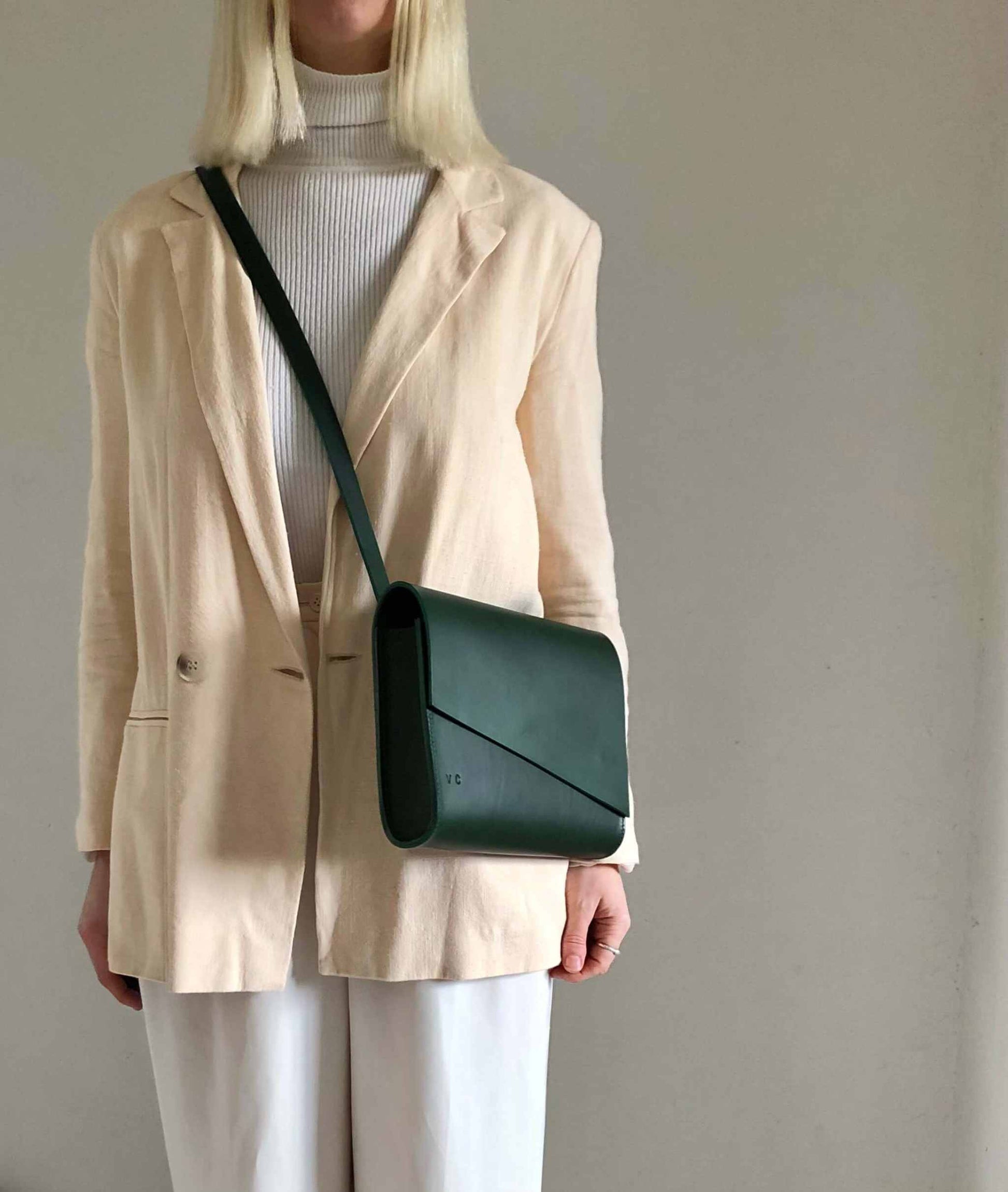 Pioneer Midi Green Leather Crossbody Bag with adjustable strap, worn by a model in a beige jacket, showcasing its sustainable design and craftsmanship.