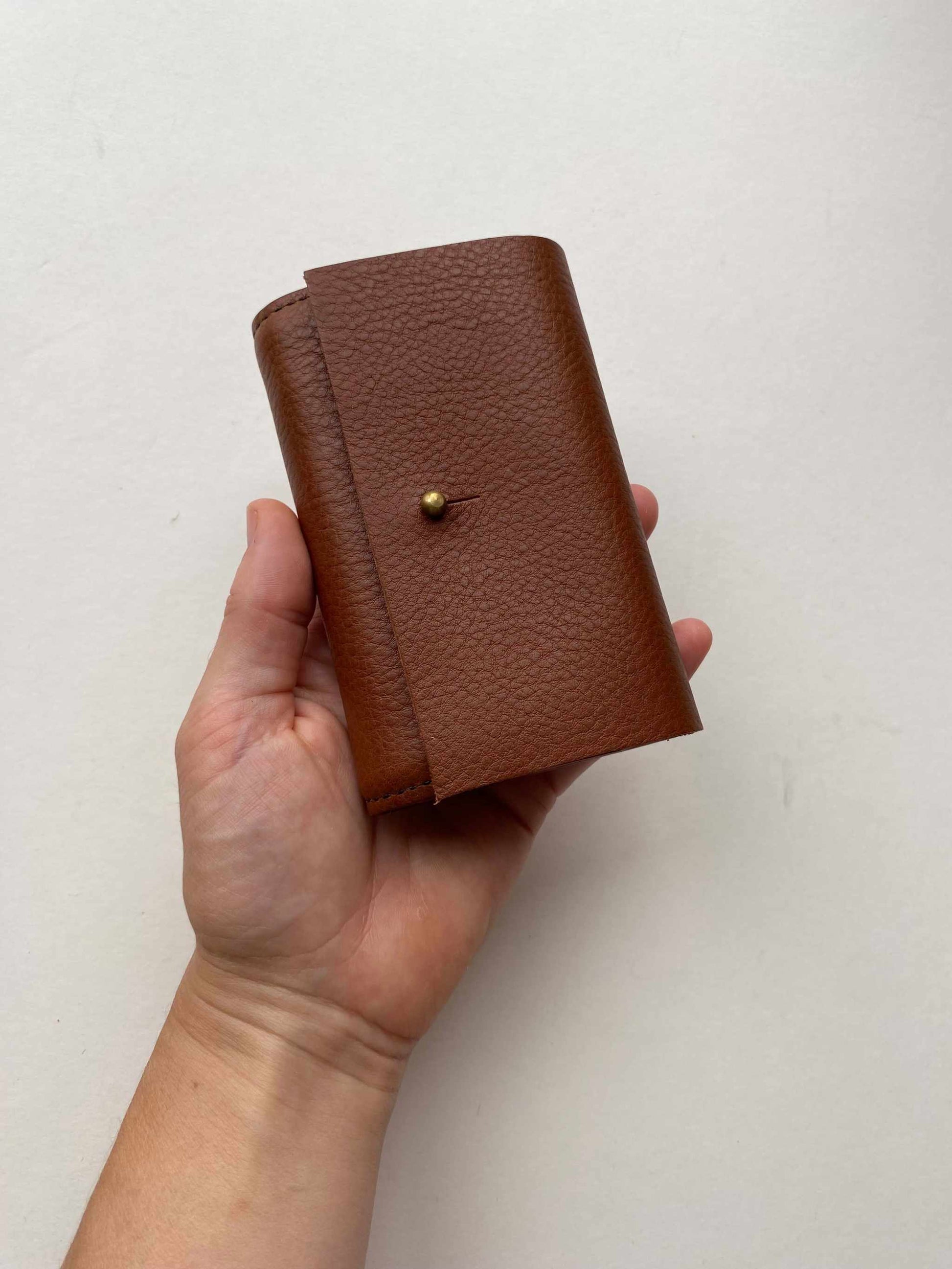 Nomad Mini Handmade Leather Wallet in tan, compact design with brass press stud and pebble texture.