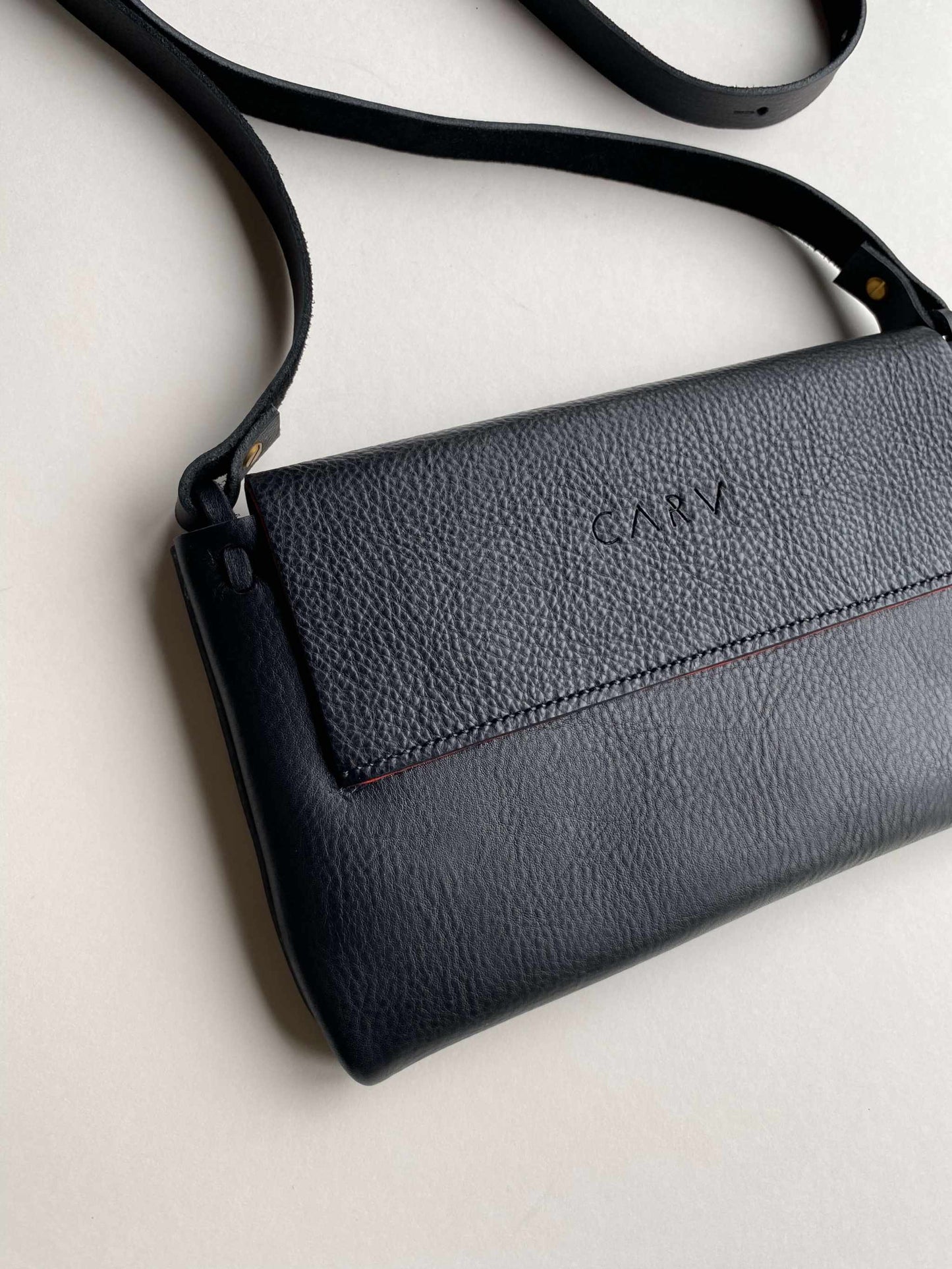 Fold Leather Crossbody Bag by CARV in black, featuring minimalist design, pebbled leather, adjustable strap, and squared flap.